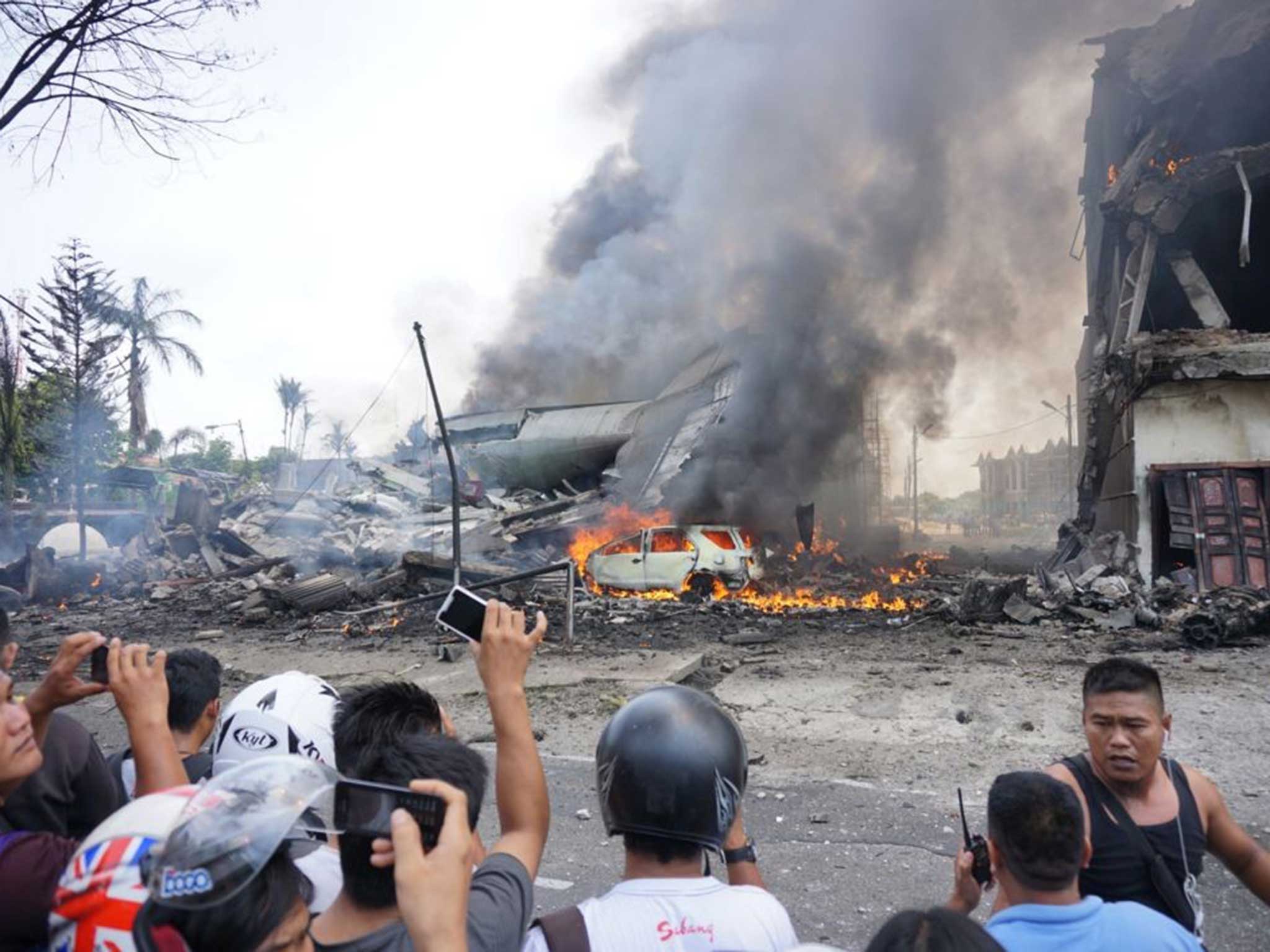 Residents take pictures of the crash as smoke billows into the sky