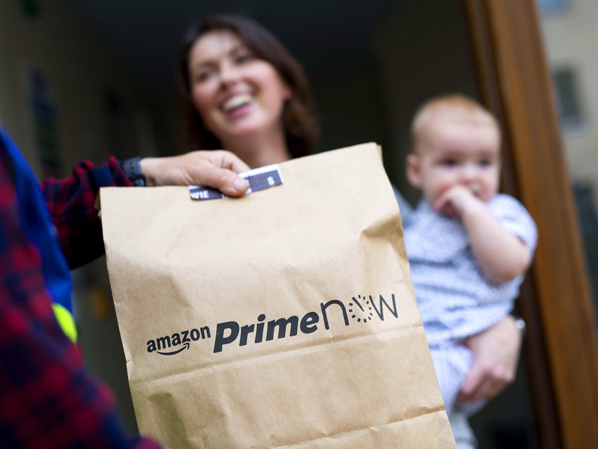 A customer in East London receiving their Prime delivery, which comes in a paper bag rather than Amazon's classic cardboard box