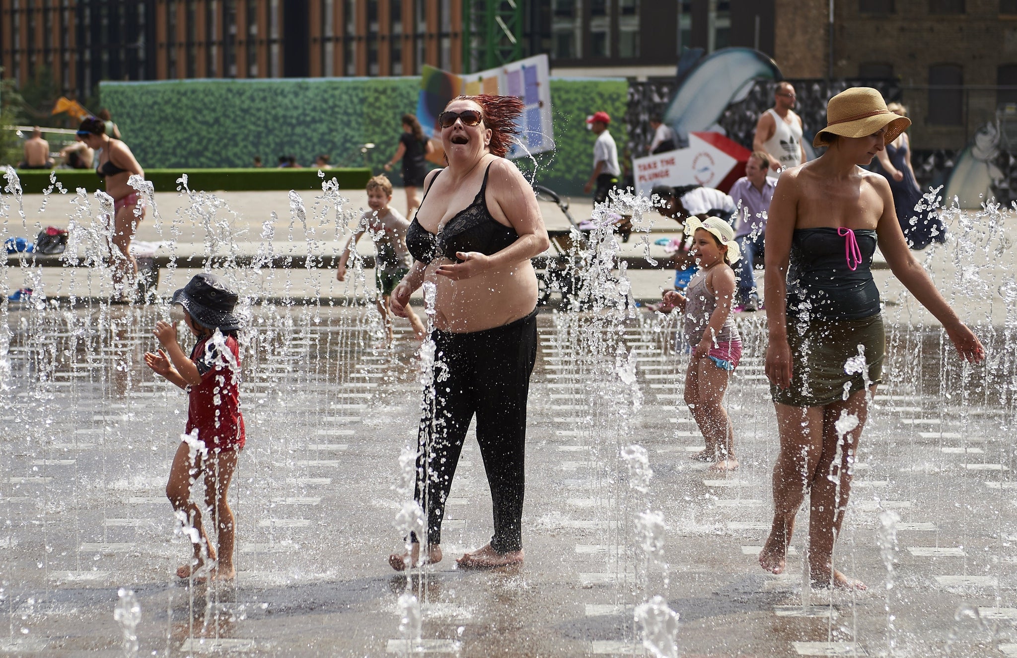 Members of the public keep cool in a water fountain in London, as temperatures soared above 30 degrees in the capital