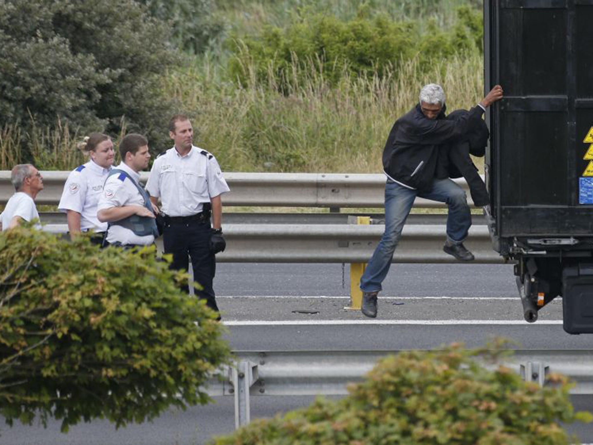 A migrant is removed from the trailer of a truck he climbed into during an attempt to make a clandestine crossing to England