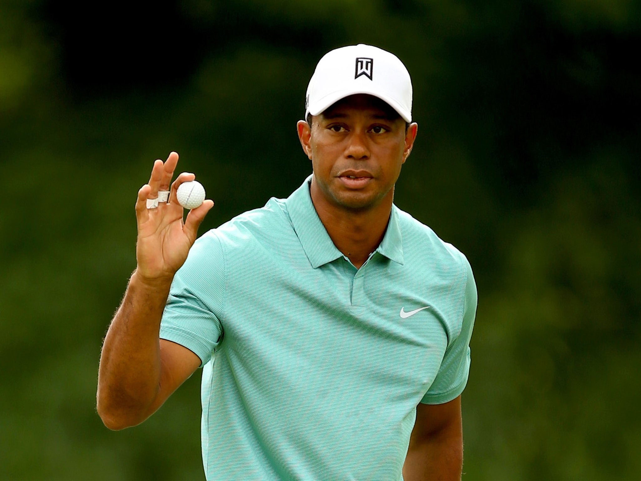 Tiger Woods waves to the gallery after holing his putt on 16