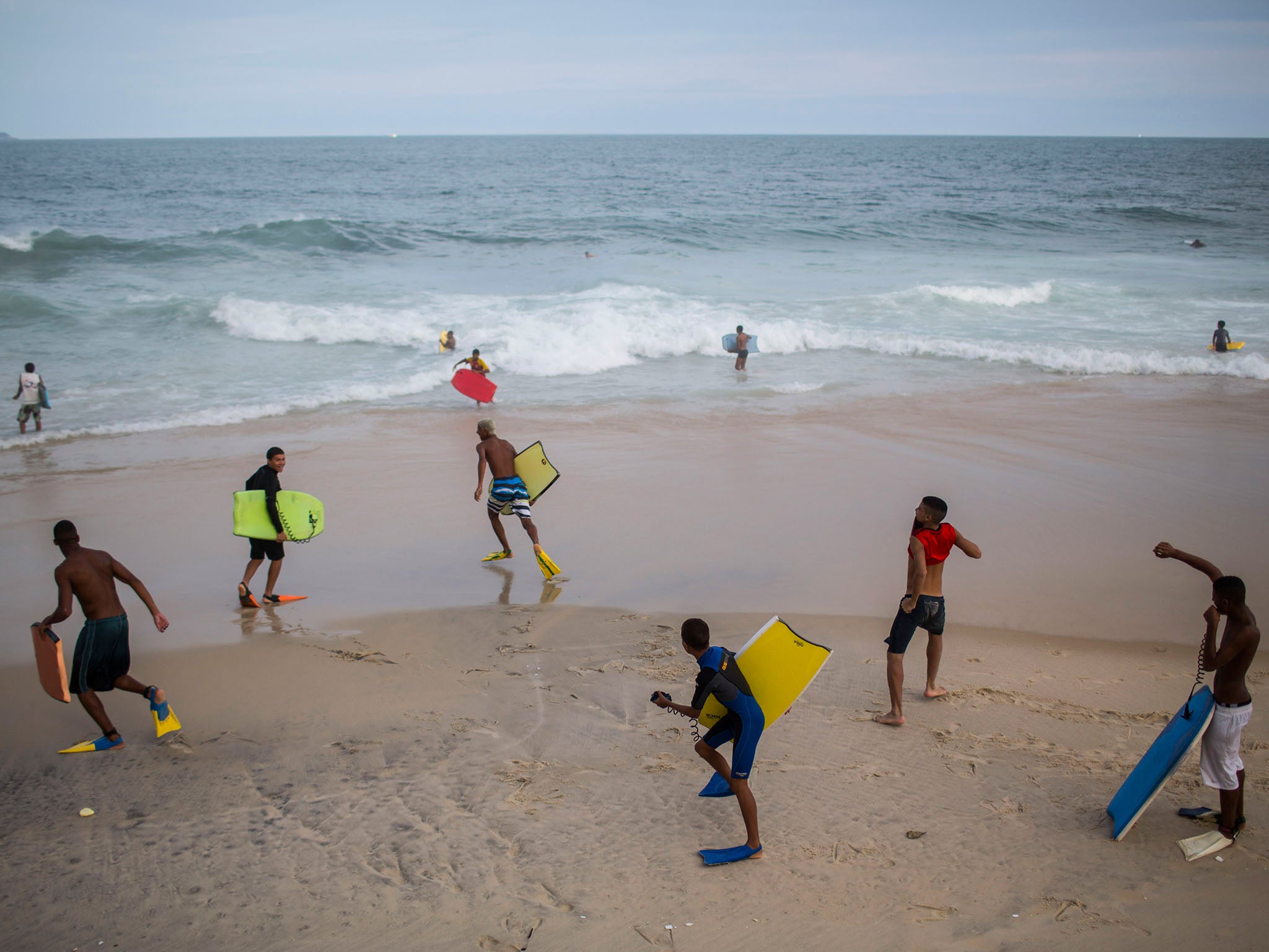 Young bodyboarders from Rocinha joke with each other as they run towards the water at Sao Conrado brach in Rio de Janeiro, Brazil (AP Photo/Felipe Dana)
