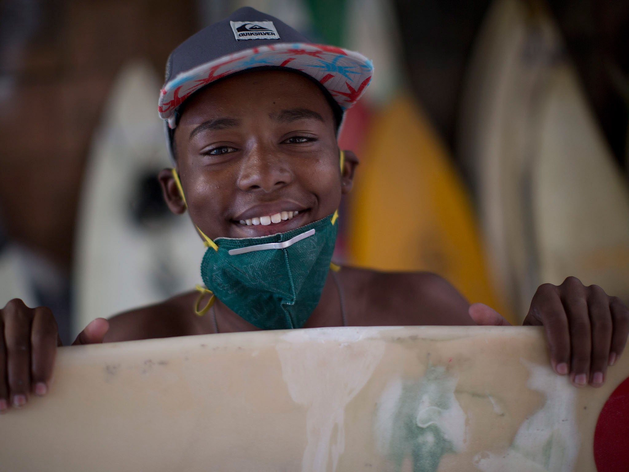 Robert Silva poses for a photo while fixing his board at the Rocinha Surf Association headquarters at Rocinha slum in Rio de Janeiro, Brazil. Along with free surf boards and clothes, kids are taught how to maintain and fix their gear. (AP Photo/Felipe Dana)