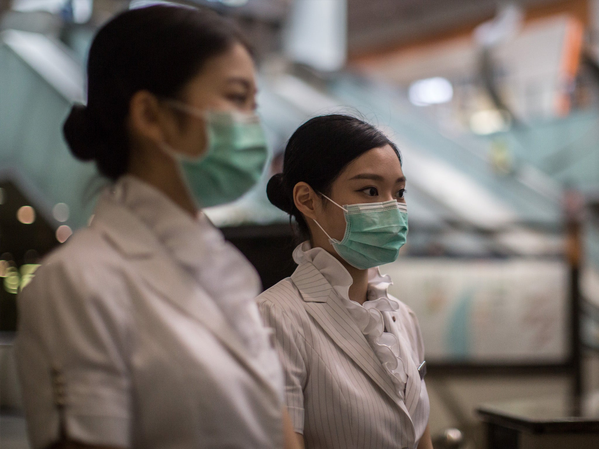 Members of staff wear face masks at Kowloon station in Hong Kong on 27 June 2015, after a 17-year-old Korean man with a fever sought medical care at a clinic in the station and has since been isolated in hospital where he is being tested for MERS, accordi