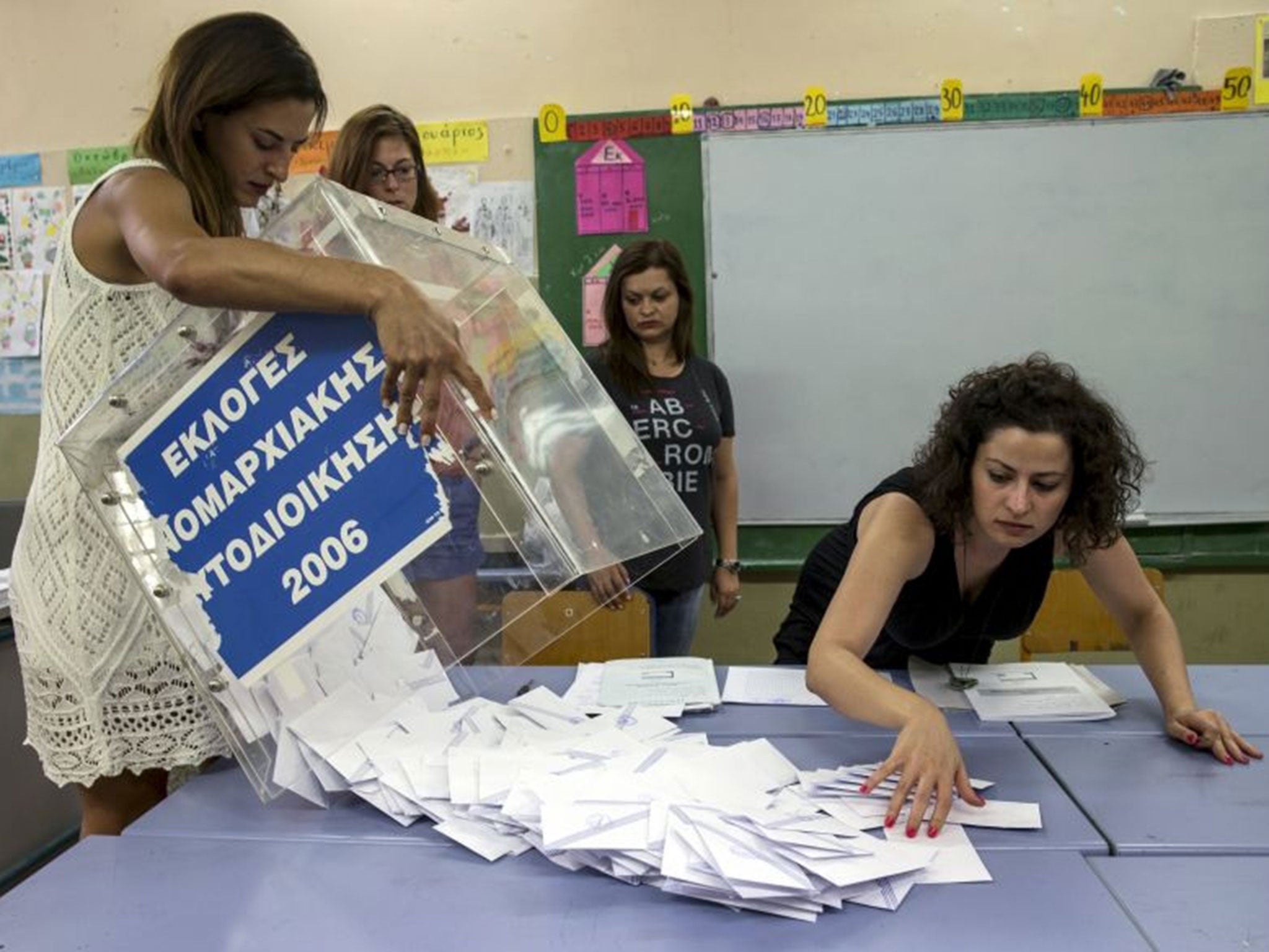 A ballot box is emptied by a voting official at the closing of polling stations in Athens