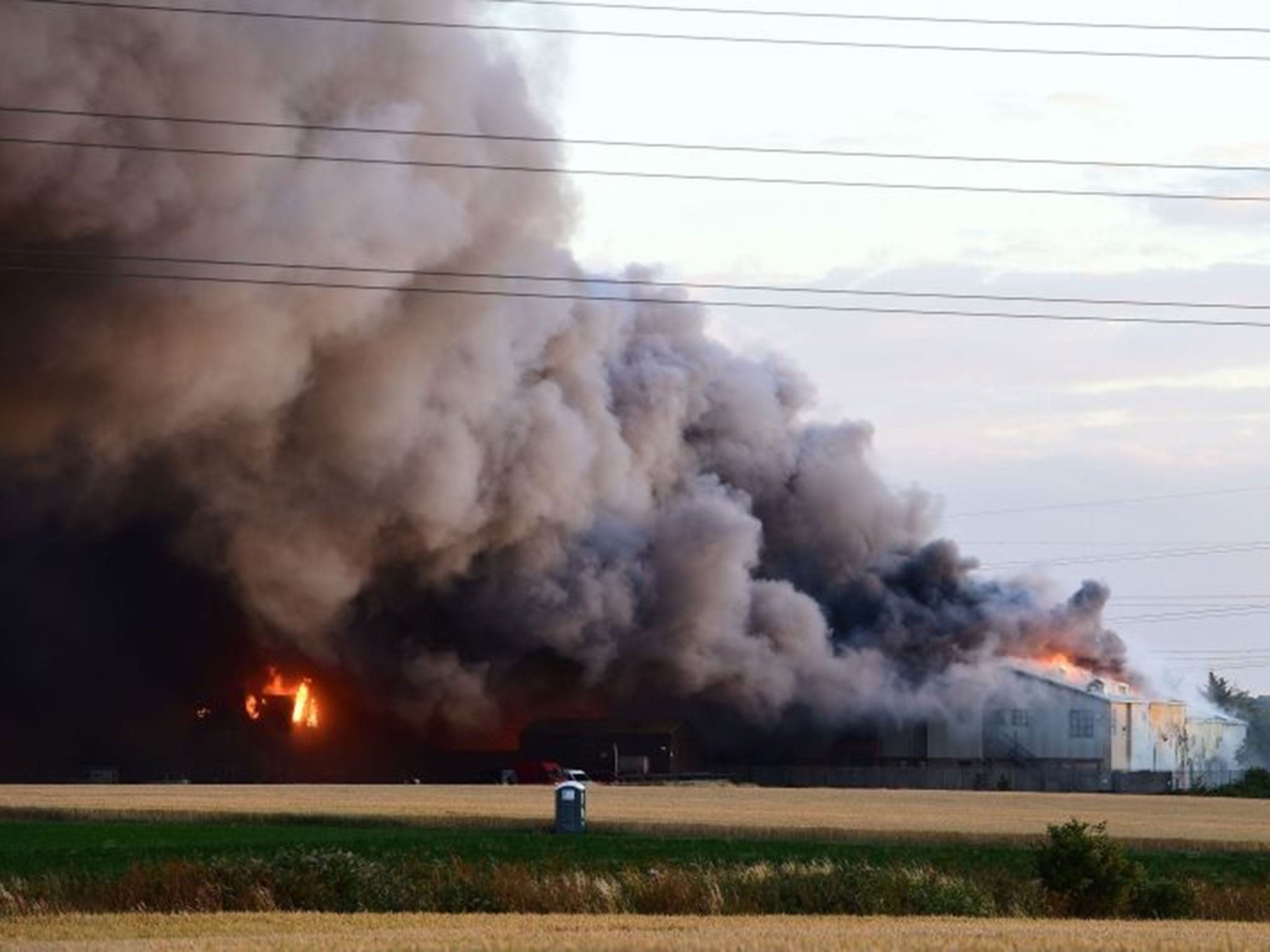 Firefighters and officers tackle a fire at a pallet yard on East Hall Lane, Rainham, Essex.