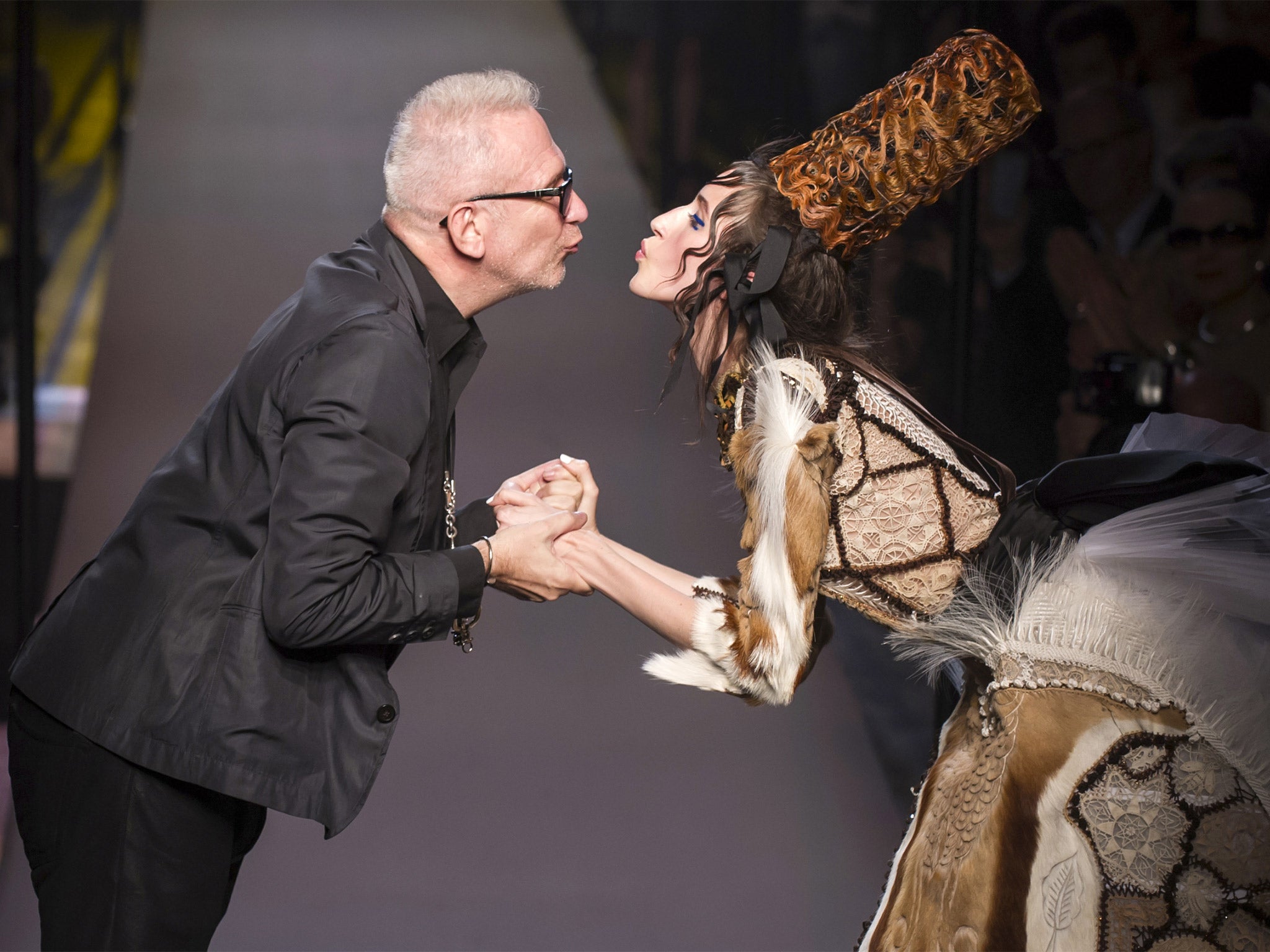 French designer Jean Paul Gaultier kisses a model during the presentation of his autumn/winter 2015 collection