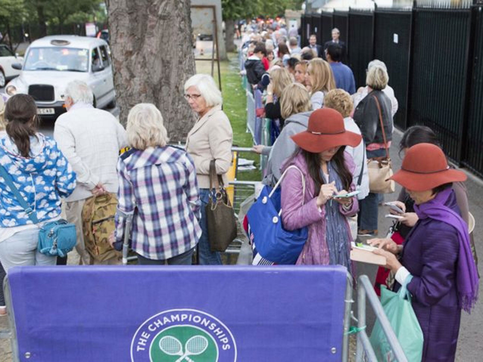 People wait in line for taxis in Wimbledon as tennis fans faced a difficult journey home due to a Tube strike which will cripple services until Friday morning.