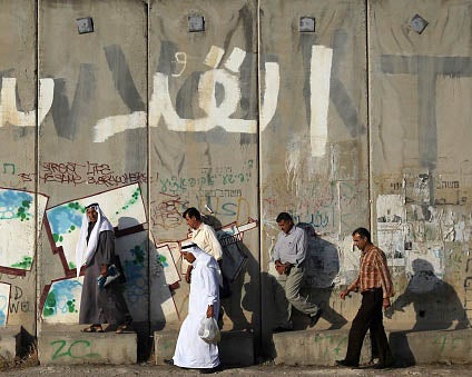 Palestinian men by the controversial separation barrier in the West Bank