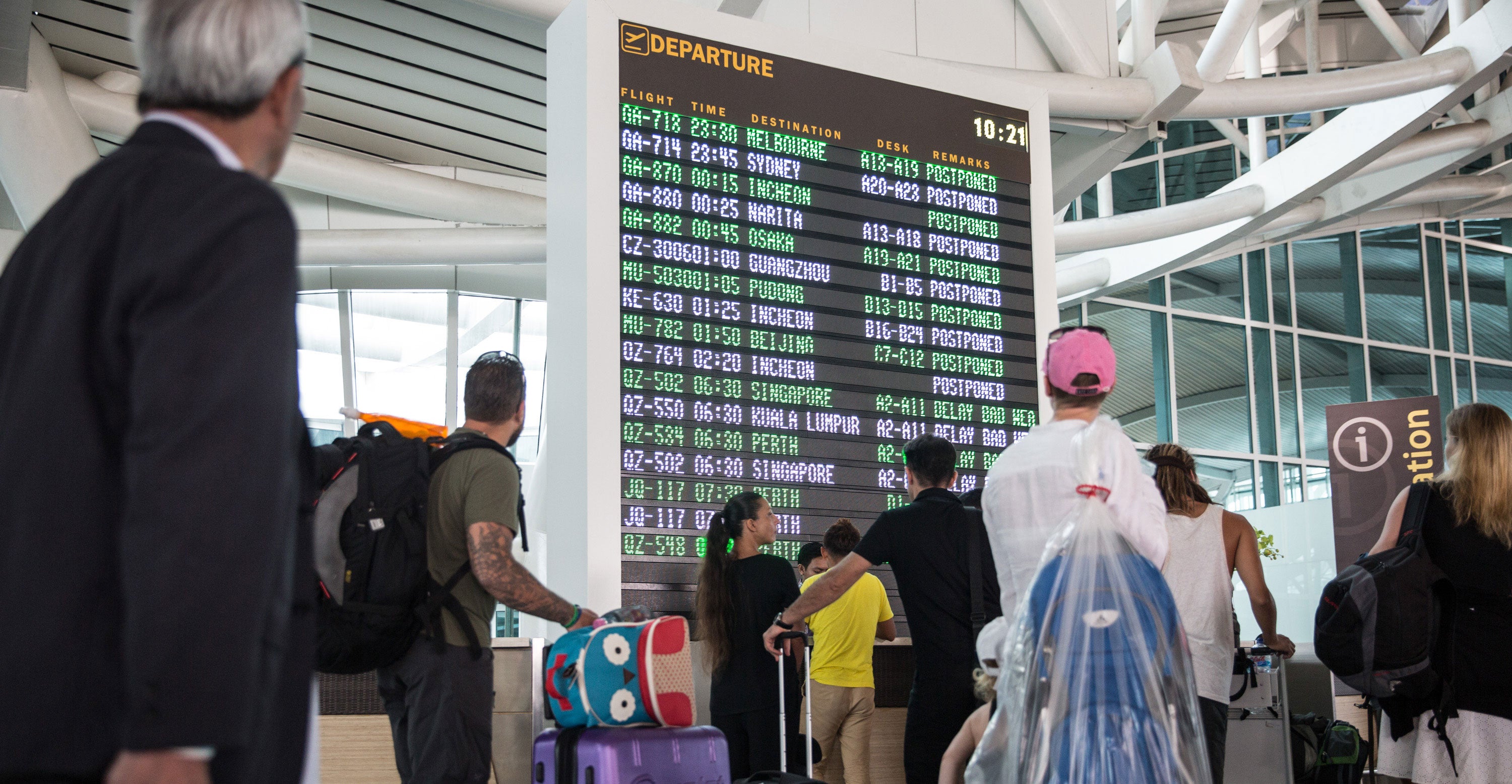 Foreign tourists look the flight schedule information board at Ngurah Rai International airport as over 270 flights are closed due to volcanic ash