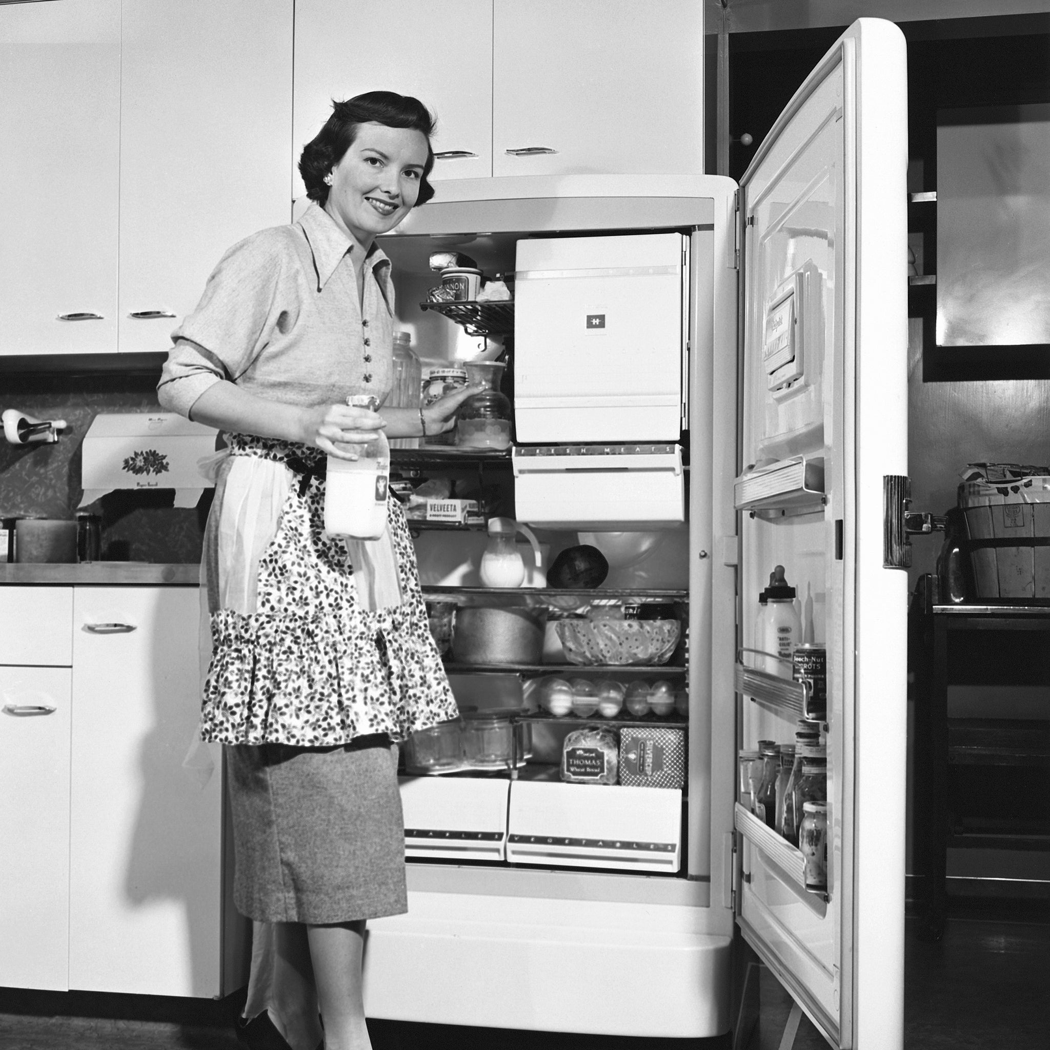 How cool: 1950s housewife beside her refrigerator