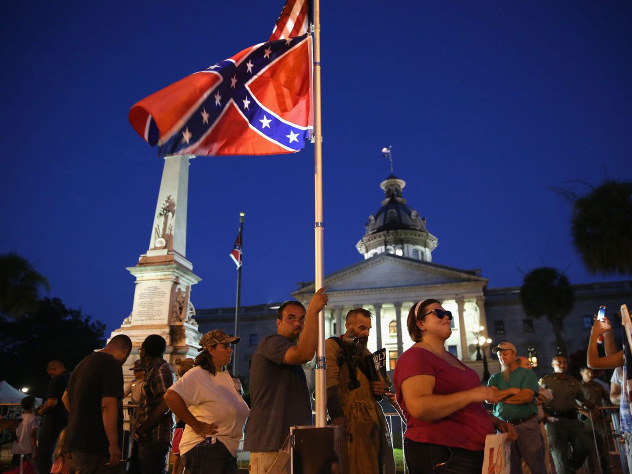 Confederate flag supporters stand outside the as "Stars and Bars" flies in front of the South Carolina statehouse on its last evening