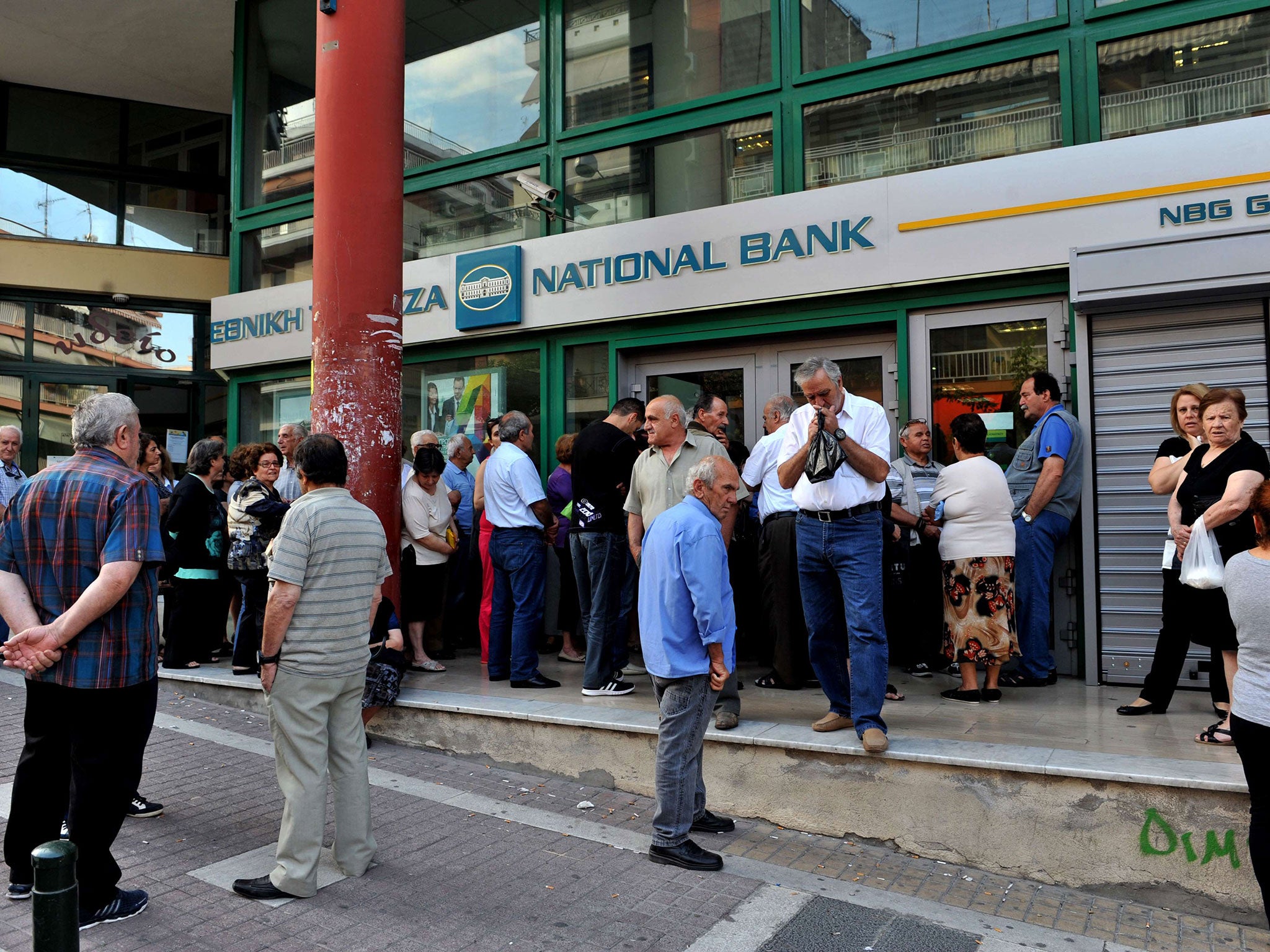 Pensioners stand outside a closed branch of the Greek National bank in Thessaloniki on June 29