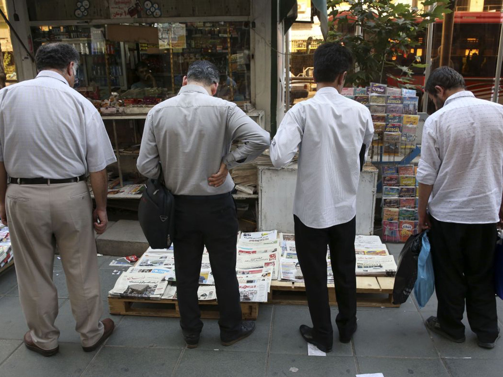 Iranian men scan newspapers in downtown Tehran, Iran. Negotiators at the nuclear talks plan to announce that they've reached a historic deal that would curb the country's atomic program