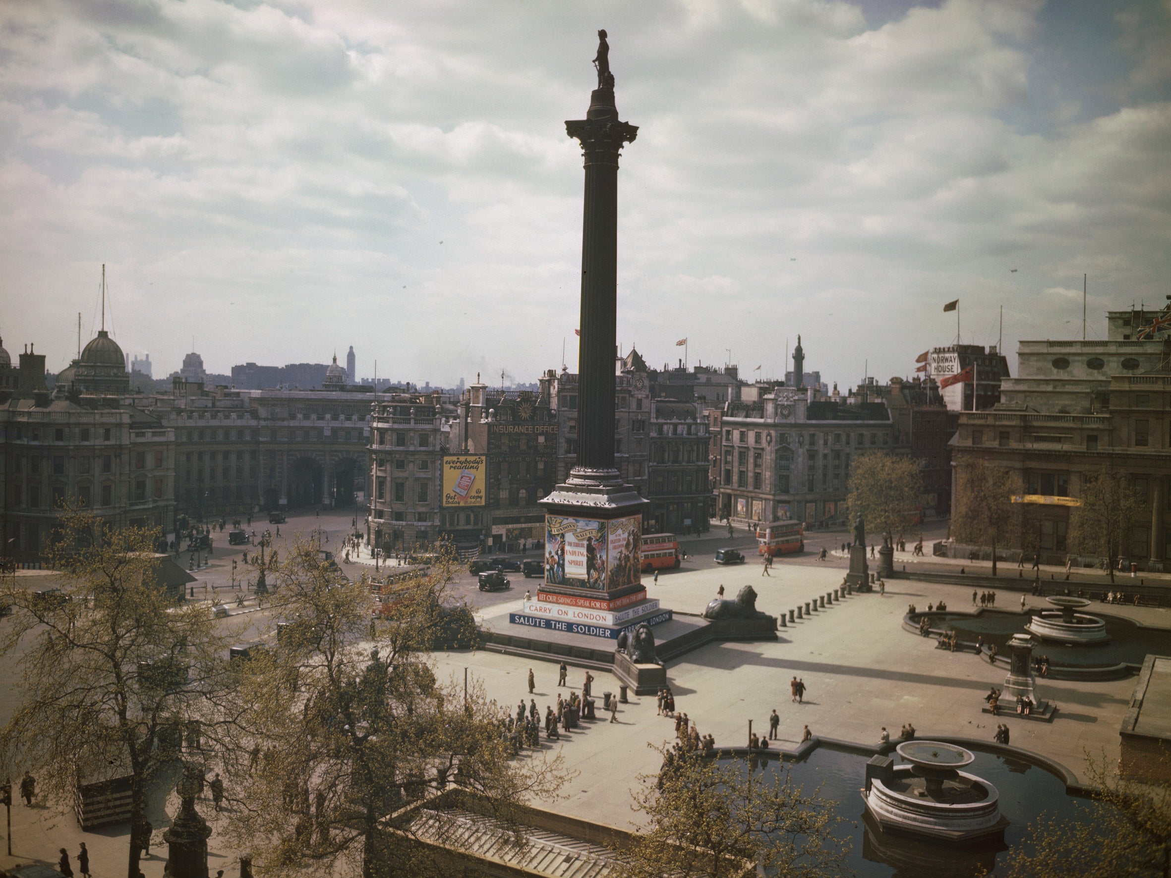 The War Effort: A view of Trafalgar Square in London showing 'Carry on London' and 'Salute the Soldier' propaganda hoardings on Nelson's Column