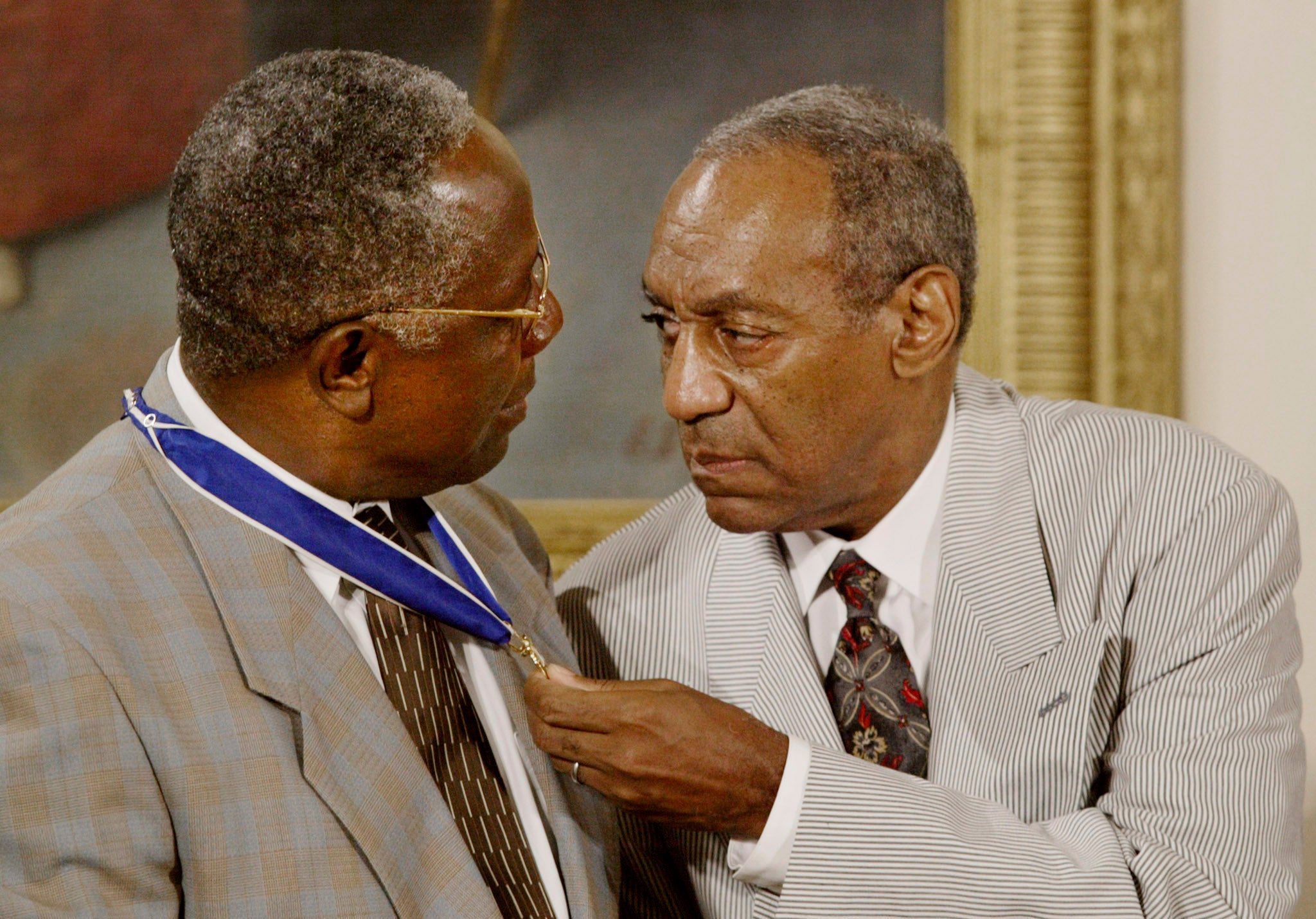 Comedian Bill Cosby checks out baseball legend Hank Aaron who received the Medal of Honor at the White House on July 9, 2002.