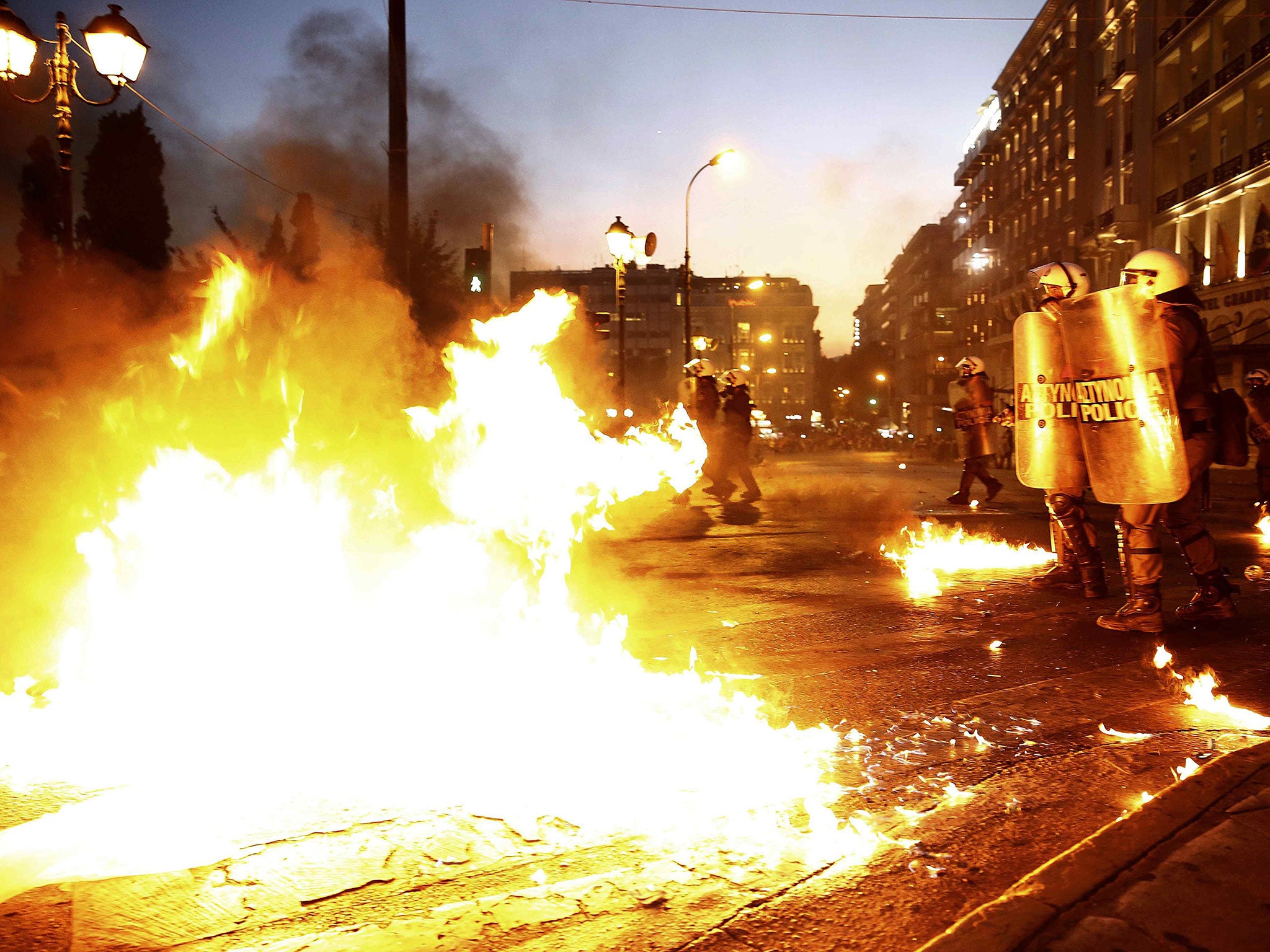 Riot police stand amongst the flames from exploded petrol bombs thrown by a small group of anti-establishment demonstrators in front of parliament in Athens, Greece July 15, 2015