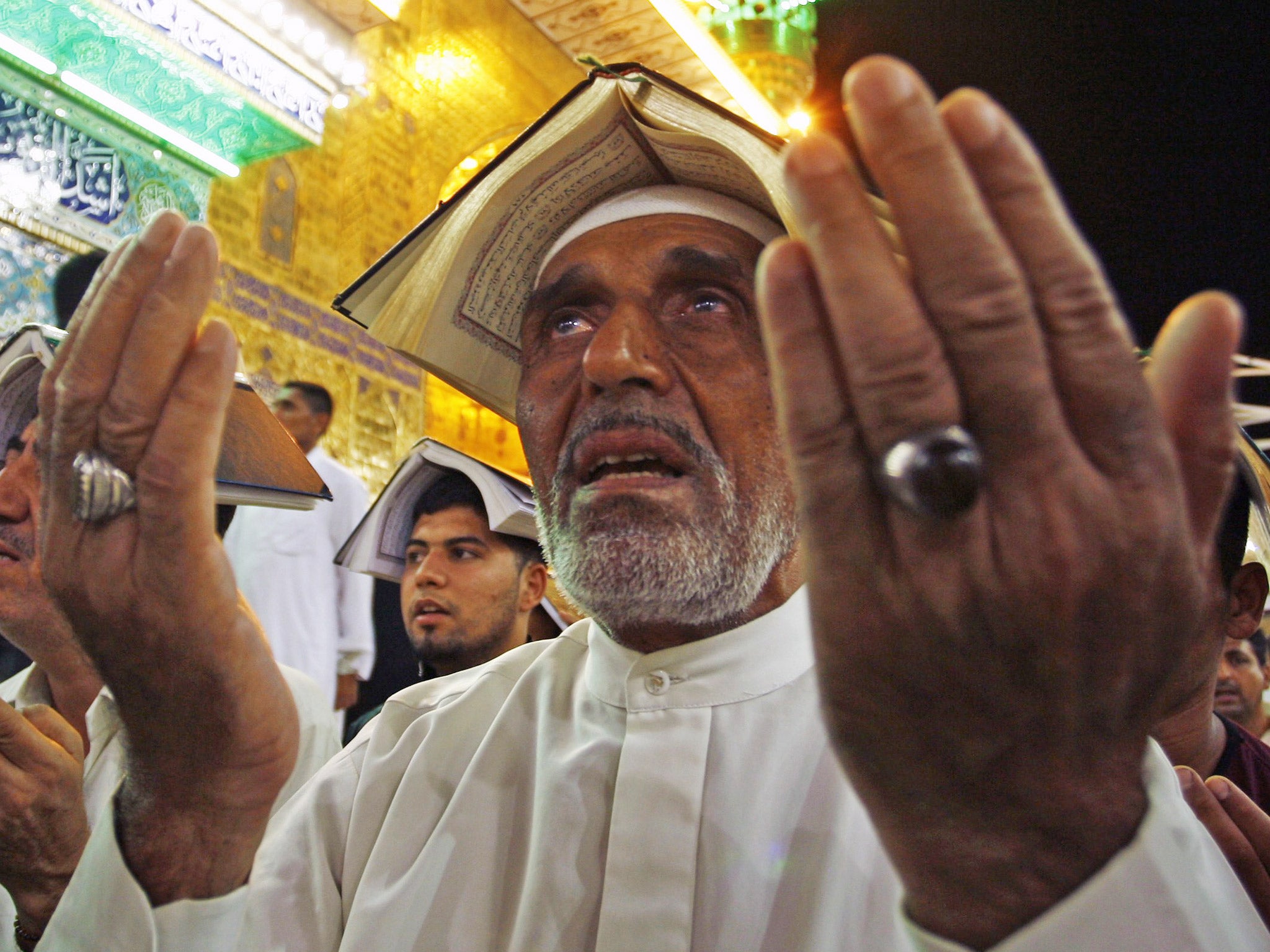 Shia muslims pray with the Koran on their heads in during Lailat al-Qadr (Night of Power) in the holy Iraqi city of Najaf