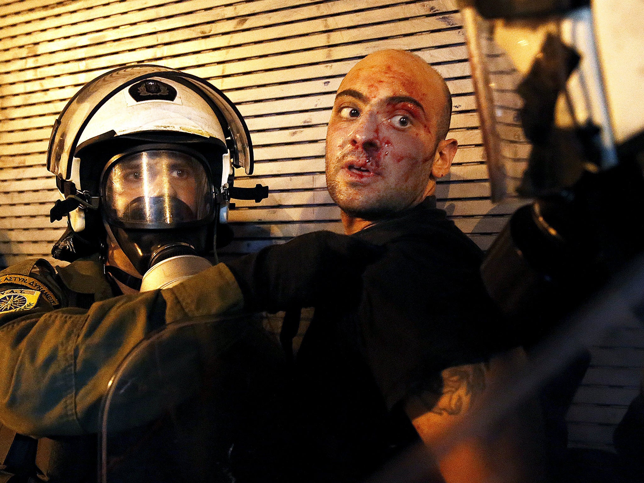 A protester bleeds as he is arrested by riot police following clashes