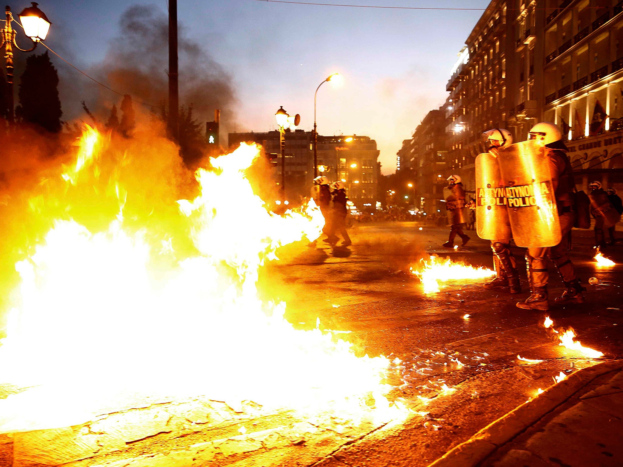 Riot police stand amongst the flames in front of parliament