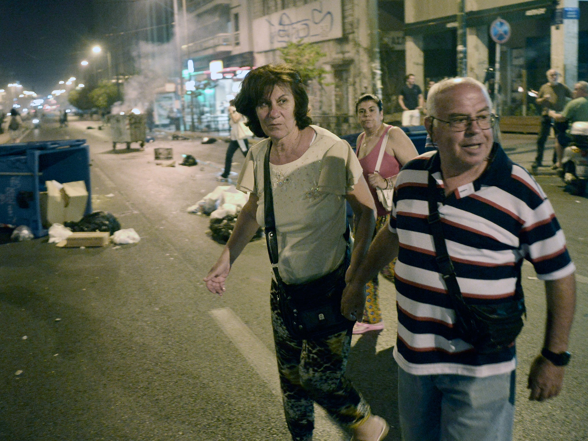 Tourists watch as debris burns on the streets following clashes between protestors and riot police