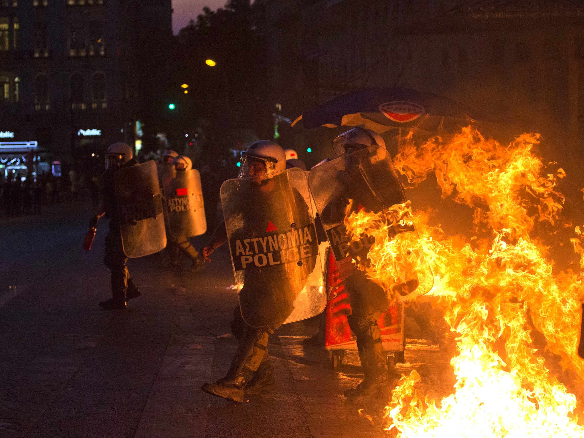 Riot police officers run away from fire