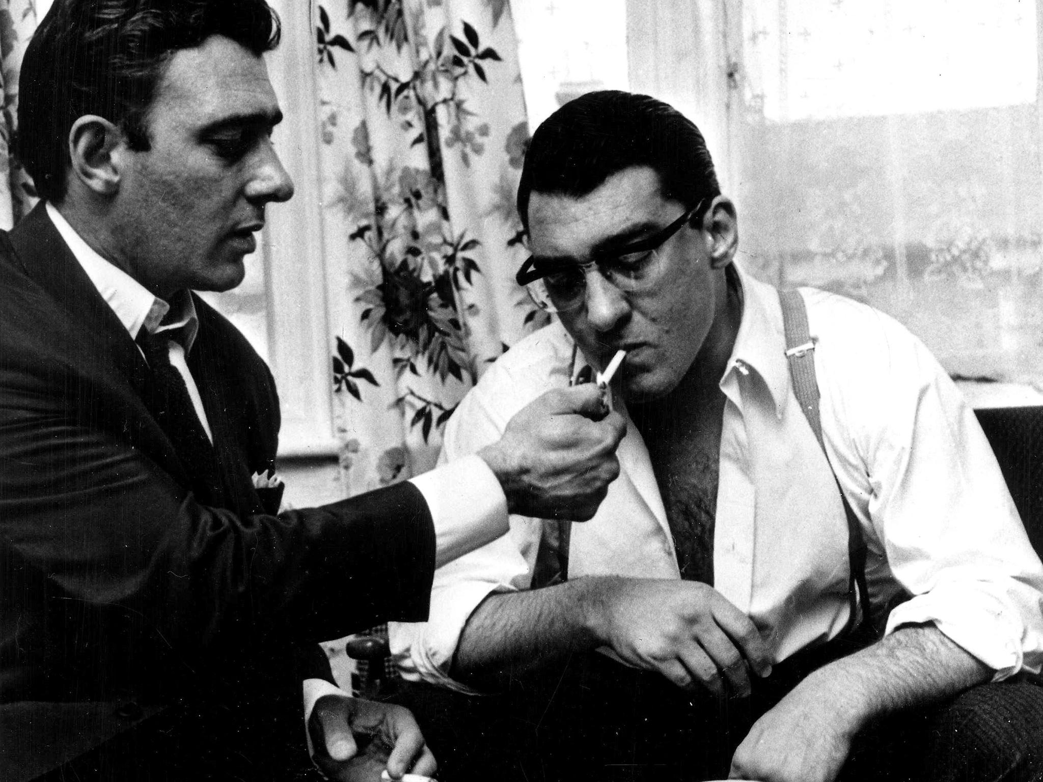 East End London gangster Reggie Kray lights up a cigarette for his twin brother Ronnie in 1969.