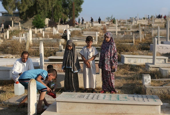 This Palestinian family visit the grave of a relative to read D'uaa at a cemetery in Gaza City's eastern suburb of Al-Shejaiya (via MAHMUD HAMS/AFP/Getty Images)