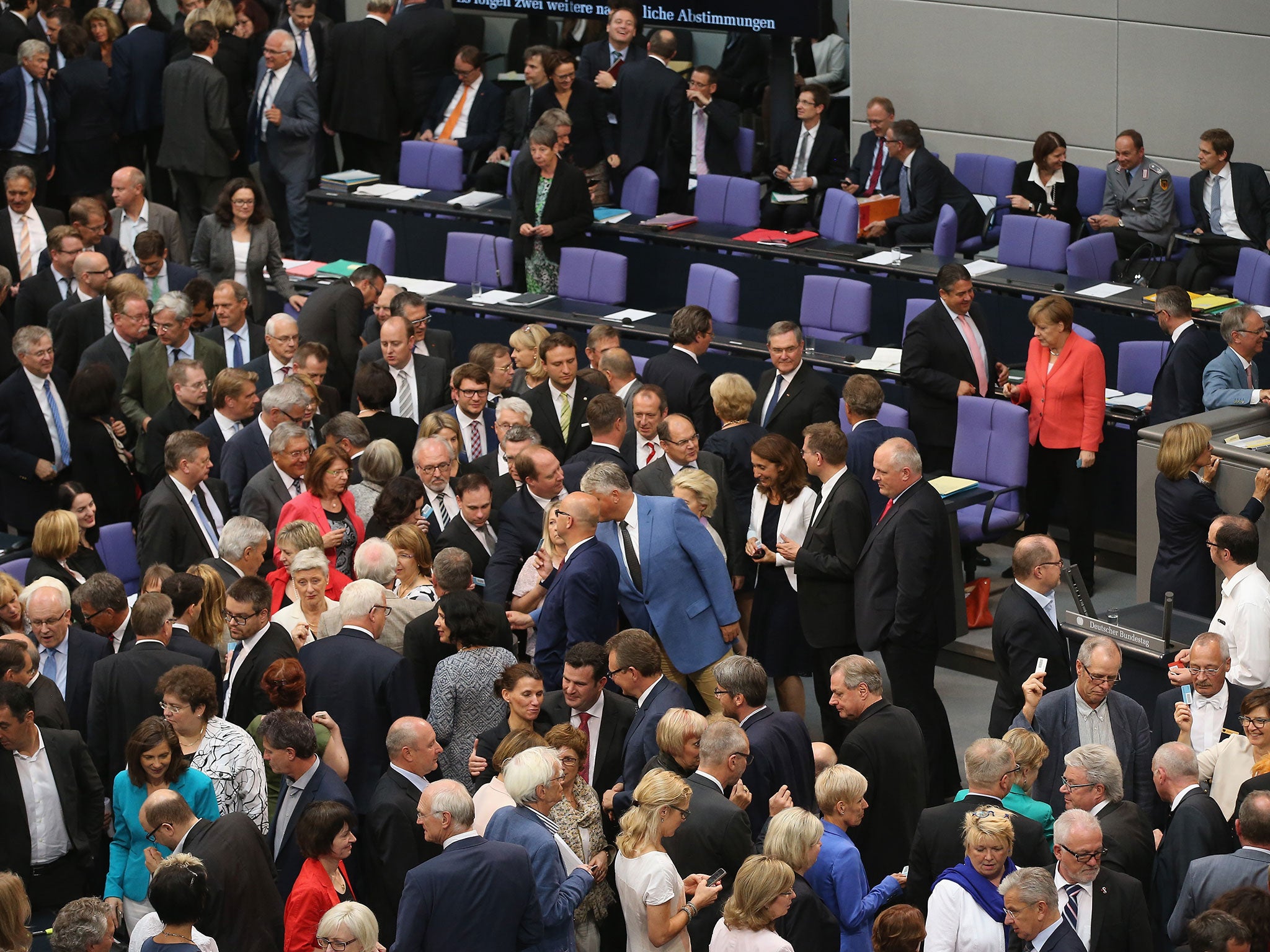 Parliamentarians, including German Chancellor Angela Merkel (R, in red) cast their ballots during votes over the third EU financial aid package to Greece