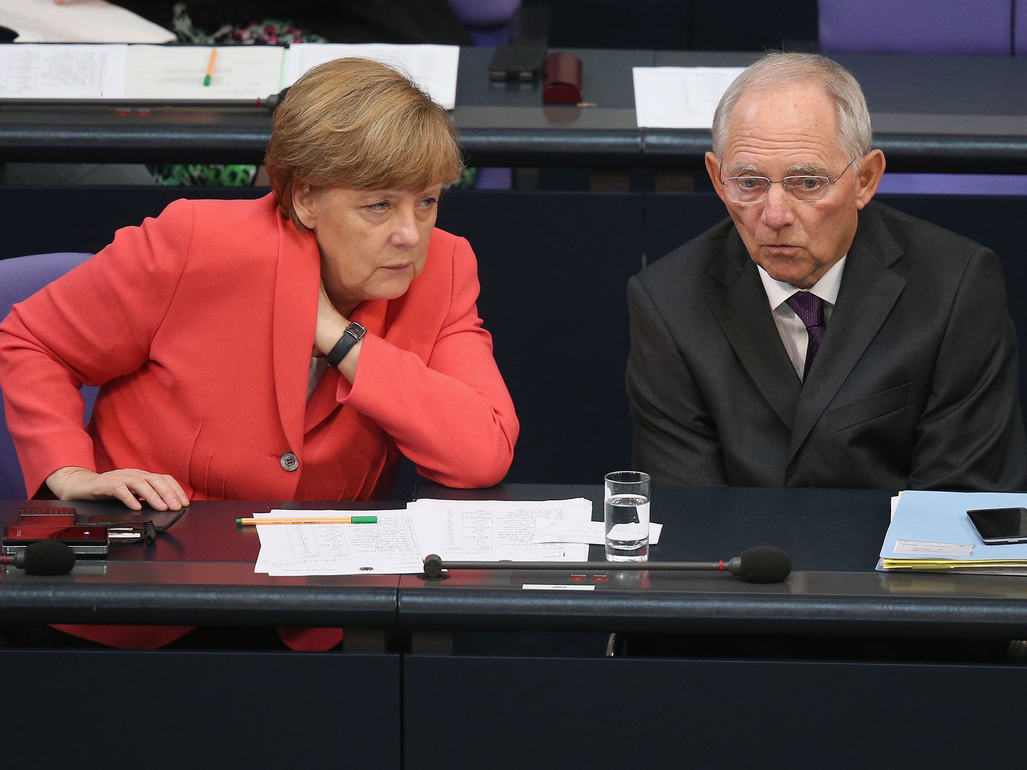 Angela Merkel and Finance Minister Wolfgang Schaeuble speak with one another during debates prior to votes over the third EU financial aid package