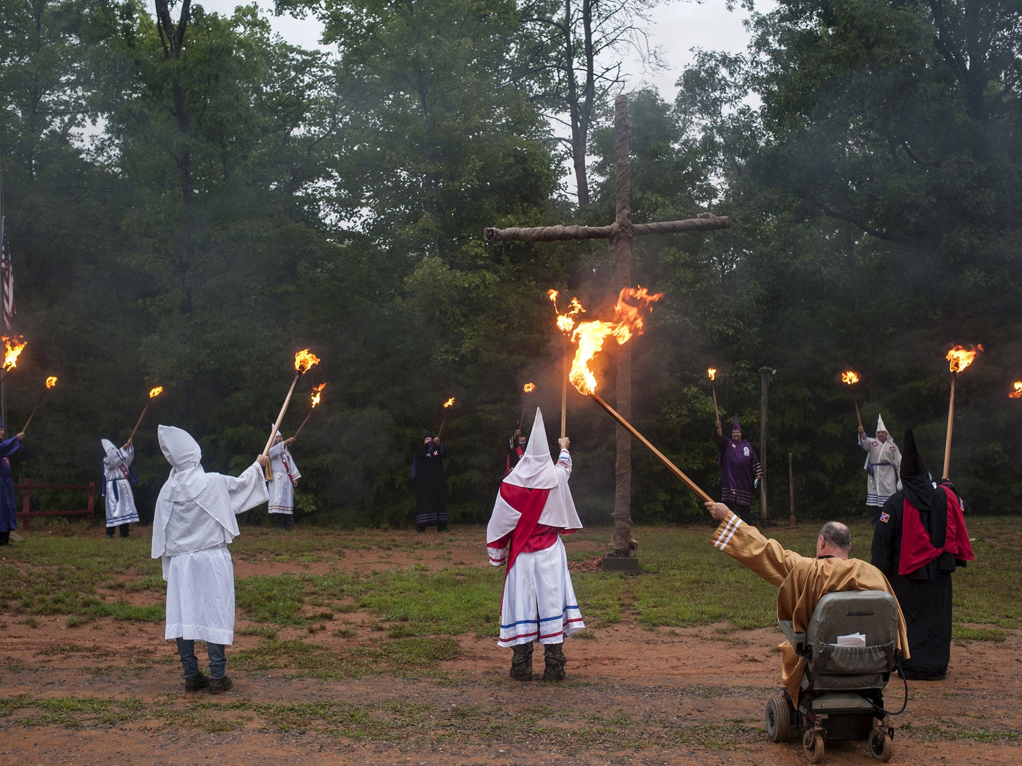 Members of the the Ku Klux Klan, raise their torches during a cross lighting ceremony