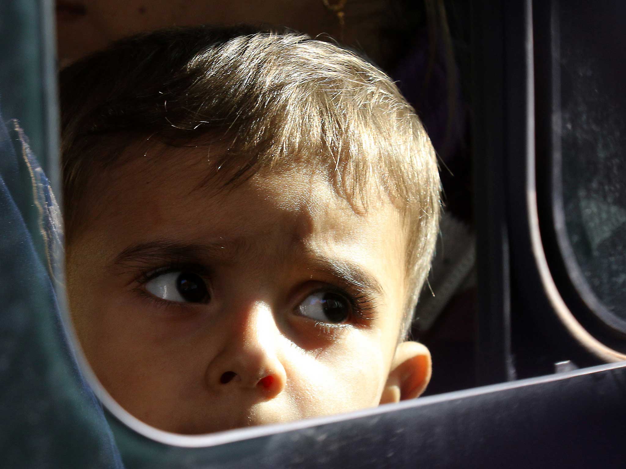 A child looks out from a bus as he arrives in Greece