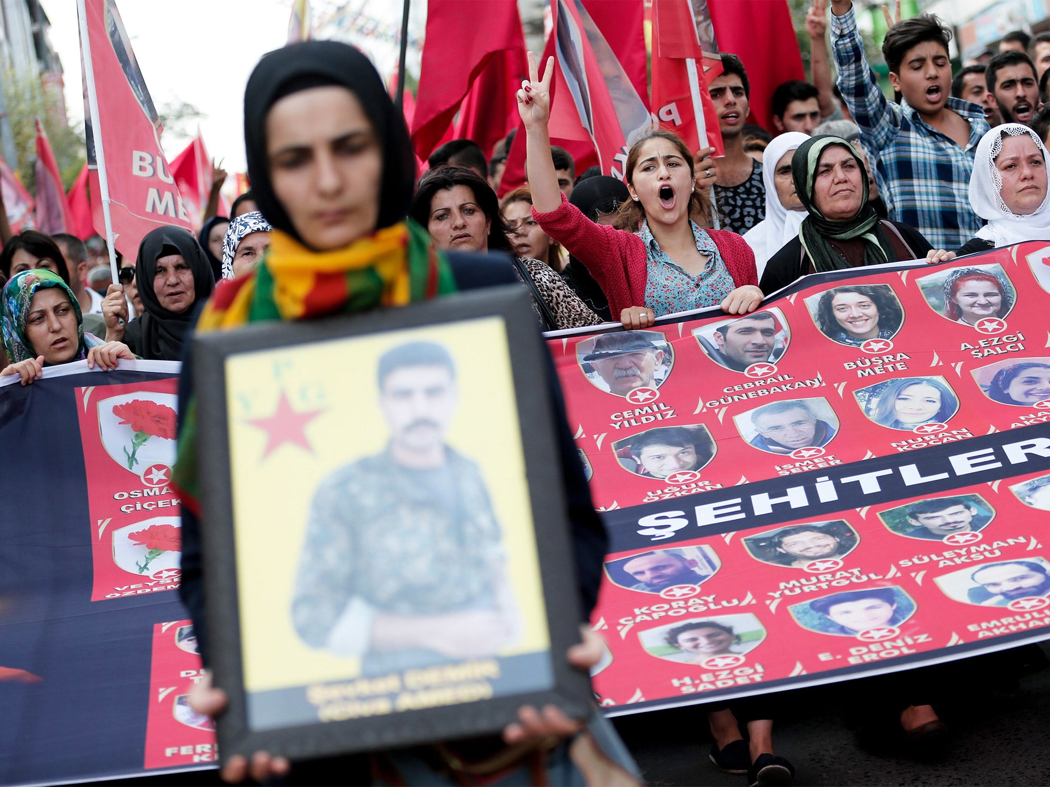 Protesters shout slogans against the Turkish government as they hold pictures of the 32 victims of the suicide bombing in Suruc during a funeral in Istanbul