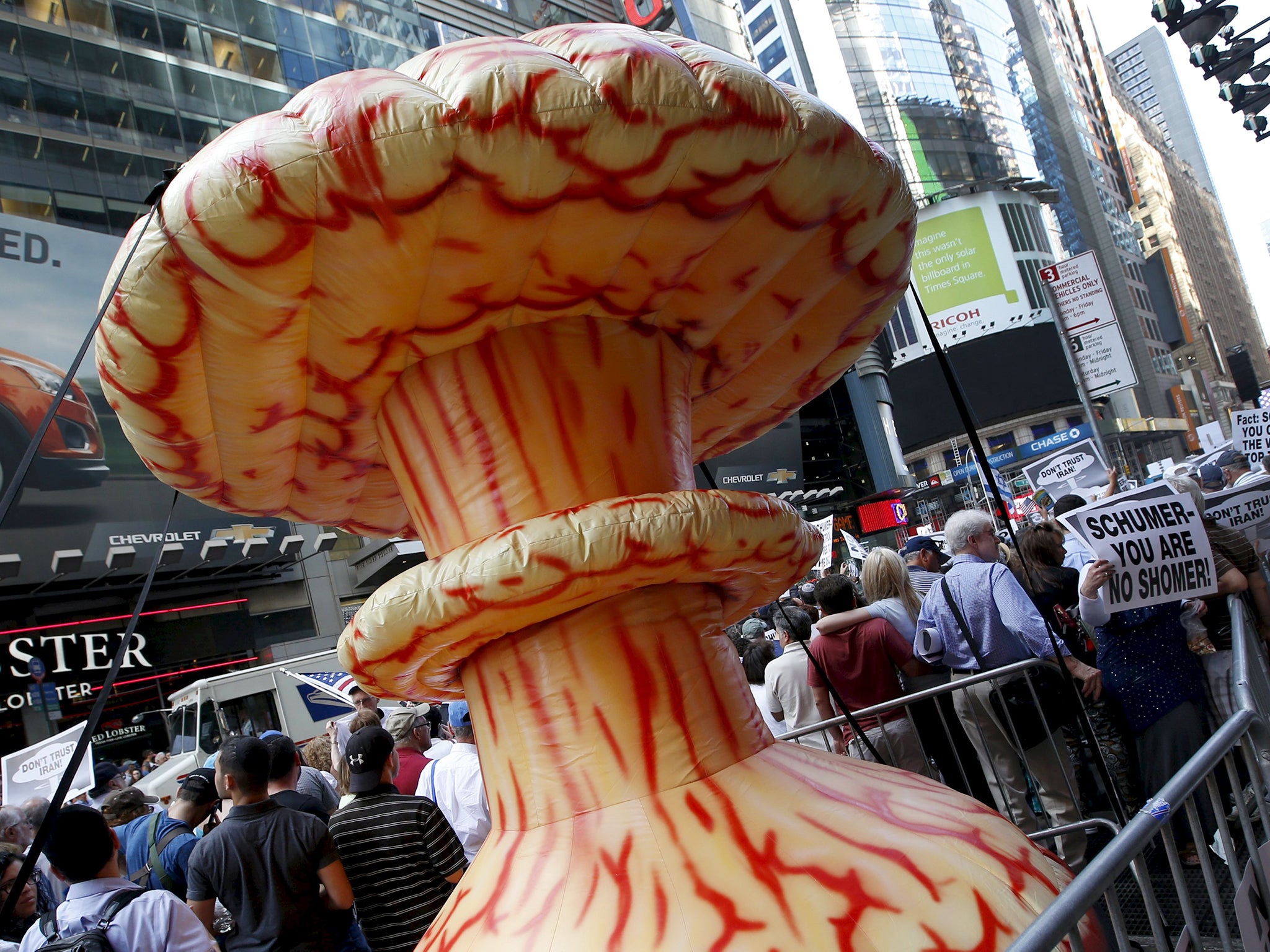 An inflatable mushroom cloud stands among demonstrators during a rally