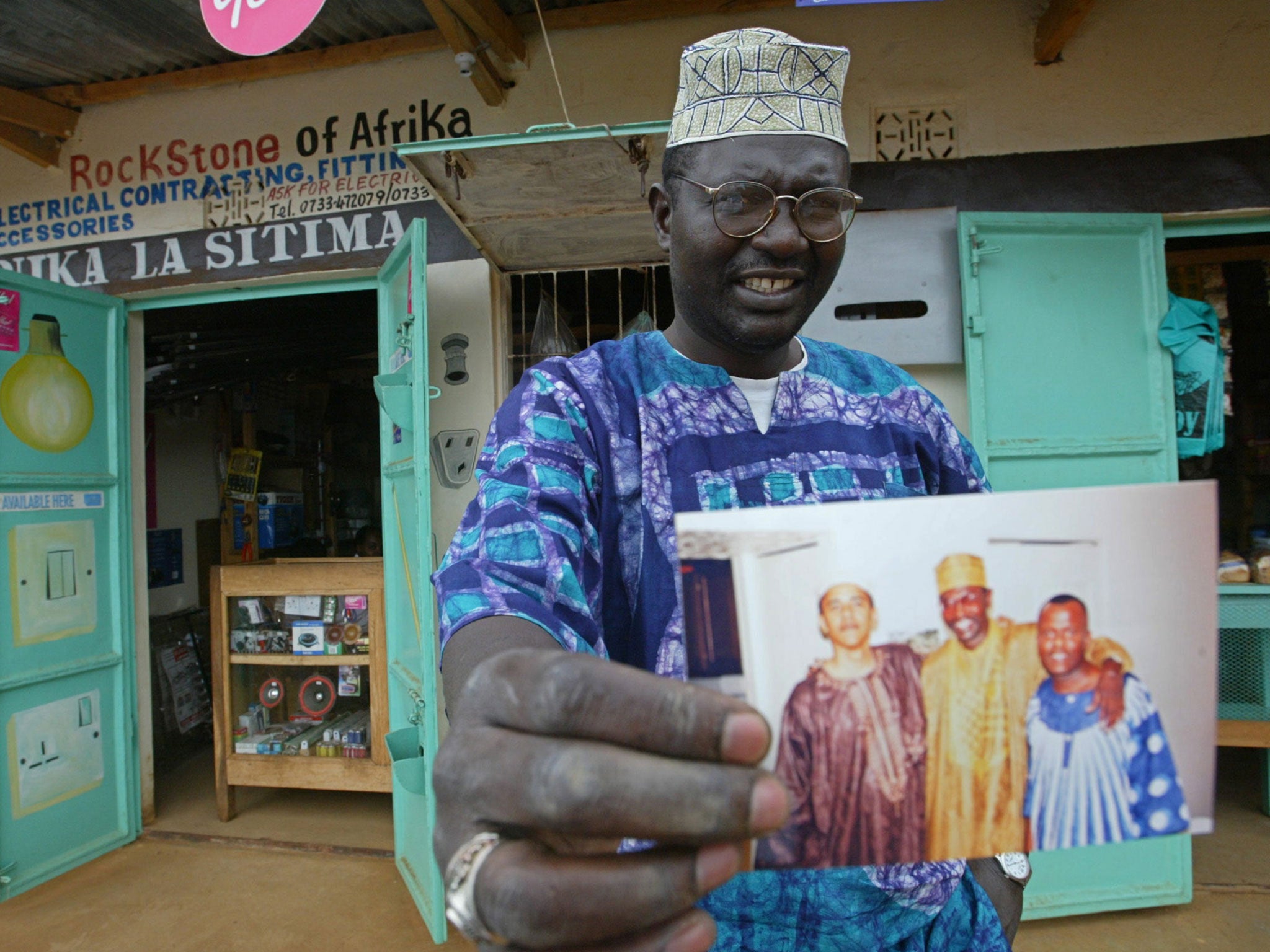 Malik Obama, the older brother of Barack, holds an undated picture outside his shop in Siaya in eastern Kenya