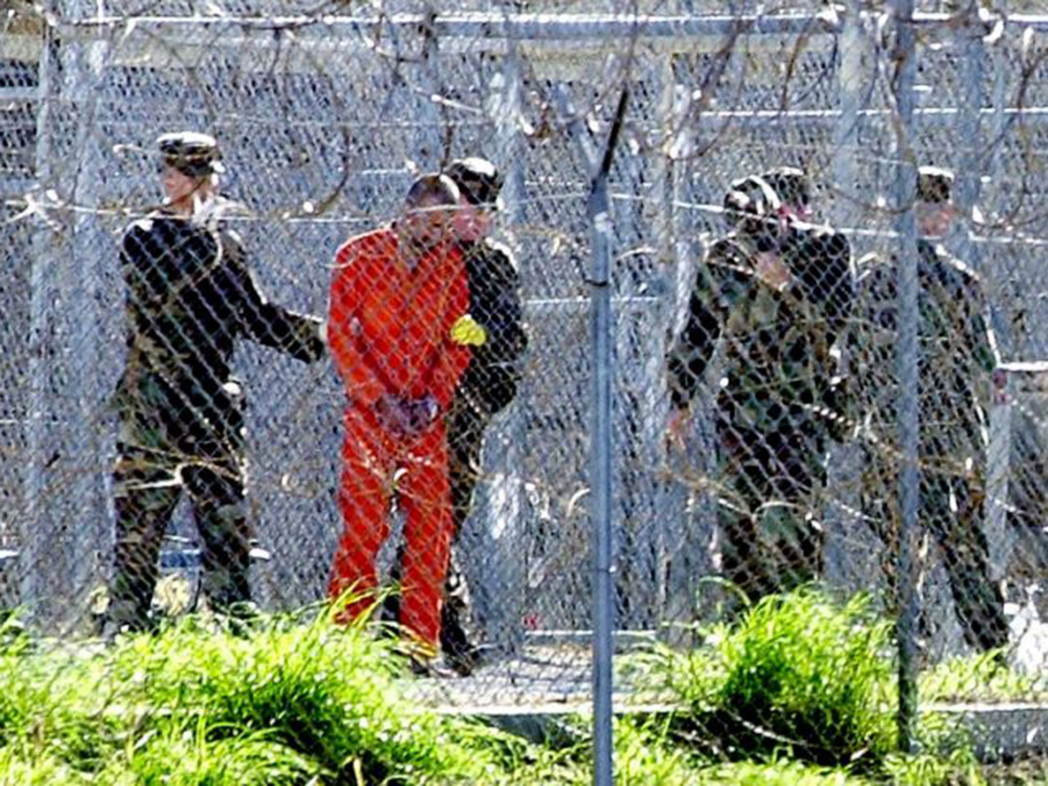 One of the 80 Al-Qaeda and Taliban detainees (2nd L) wearing an orange jump suit can be seen in his cell at Camp X-Ray