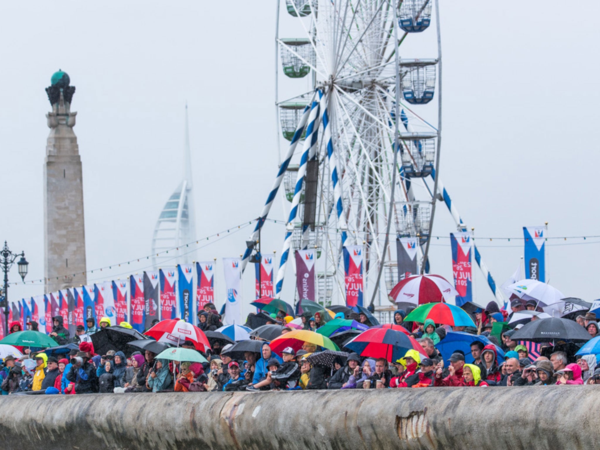 Les parapluies de Portsmoutb. Umbrellas raised as a crowd on the sea wall at Southsea watches the six boats in the America’s Cup World Series go through their paces.