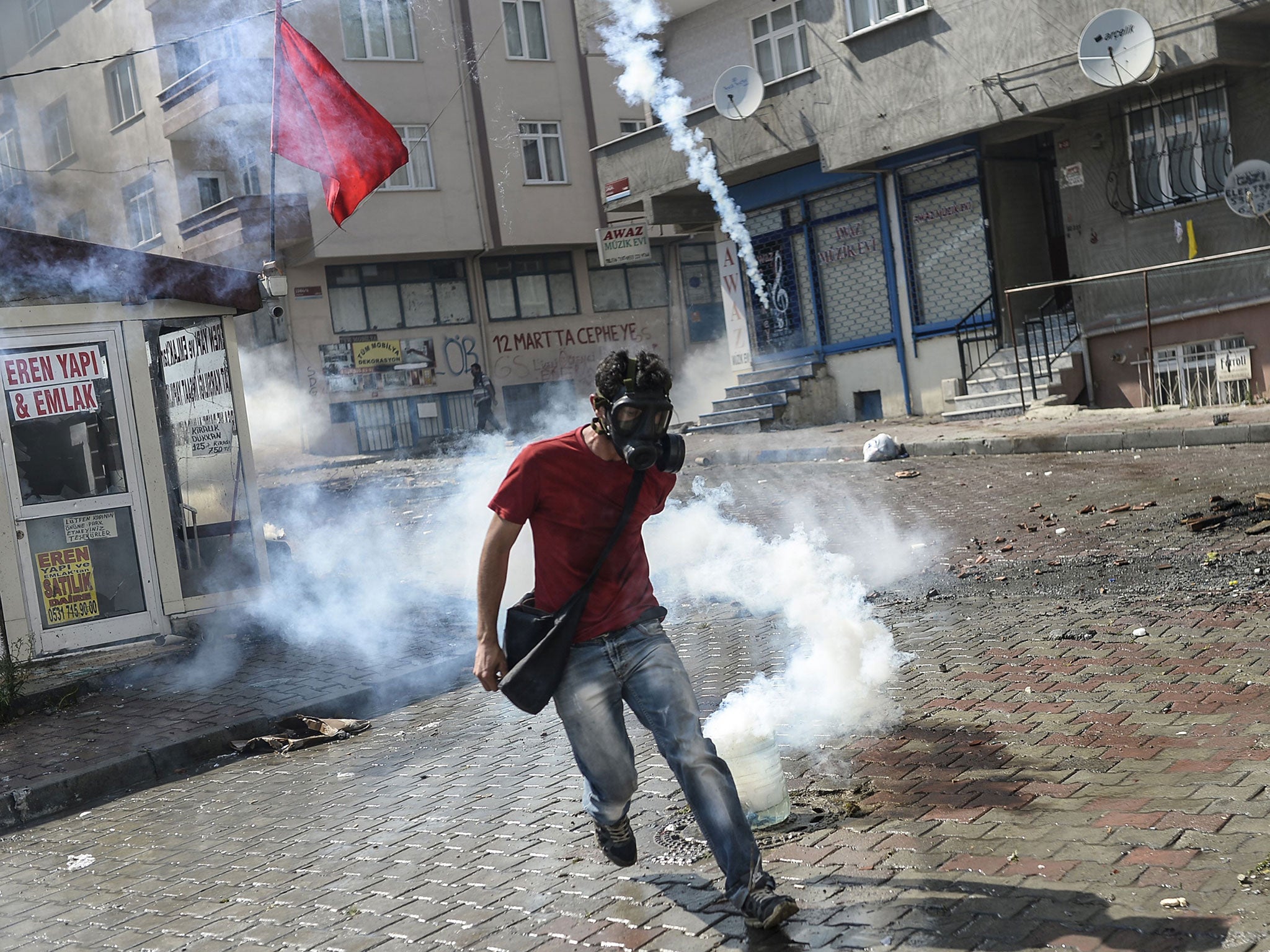 A militant flees from a tear-gas canister during clashes with police in Istanbul