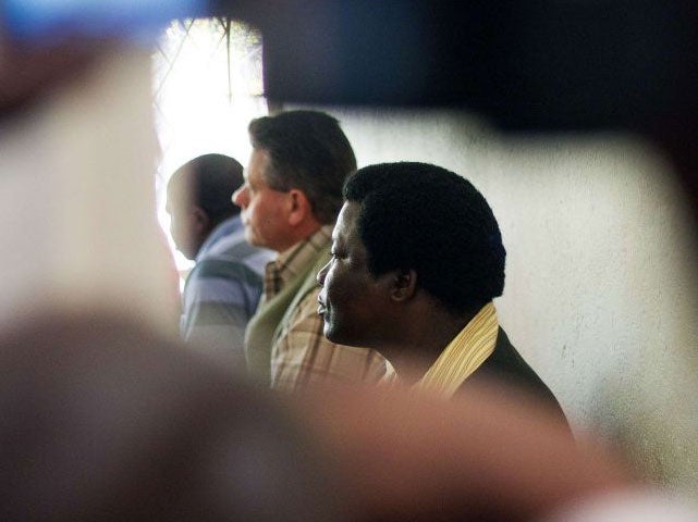 Professional Zimbabwean hunter Theo Bronkhorst (C) and local landowner Honest Ndlovu (R) sit in the Prosecutor's office at the Magistrate's Court in Hwange during proceedings on poaching charges.