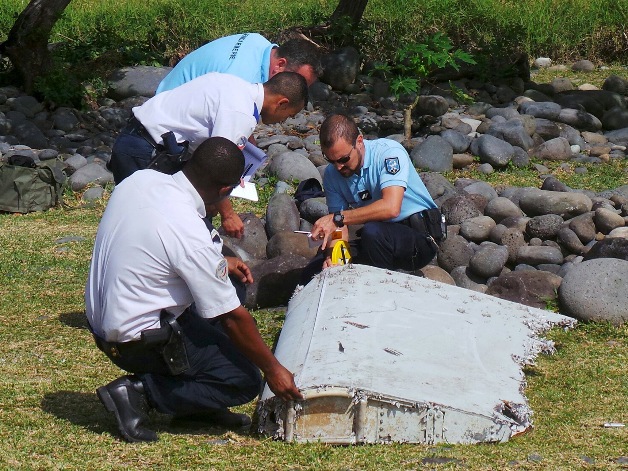 French gendarmes and police inspect a large piece of plane debris which was found on the beach in Saint-Andre, on the French Indian Ocean island of La Reunion