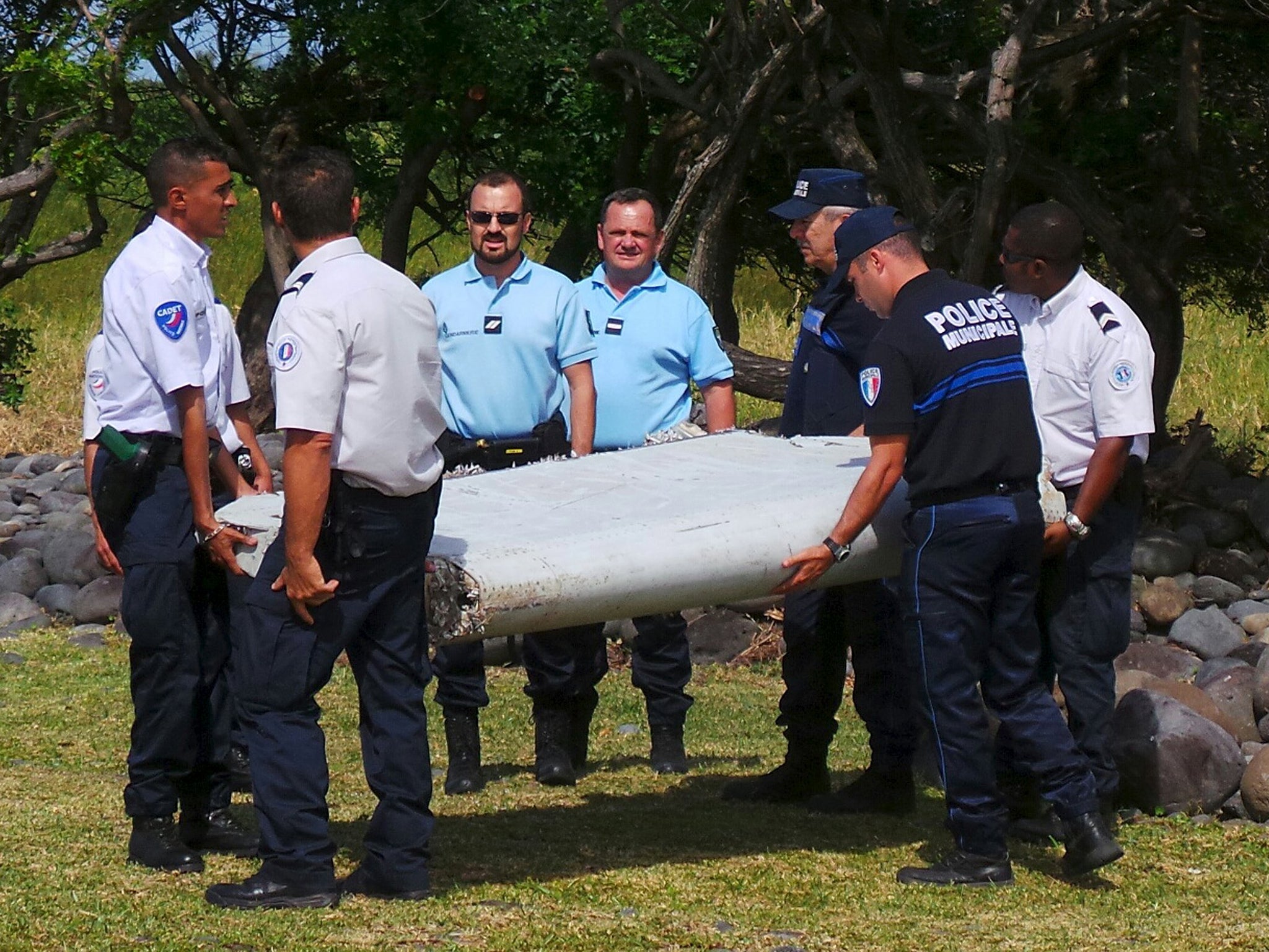 French gendarmes and police carry a large piece of plane debris which was found on the beach in Saint-Andre, on the French Indian Ocean island of La Reunion