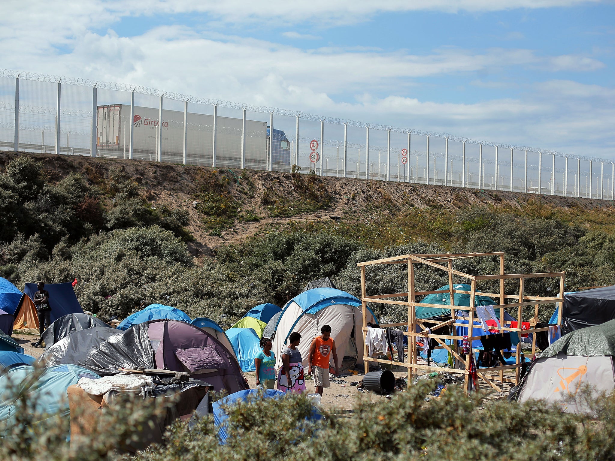 Migrants walk in a makeshift camp in Calais (Image: AP)