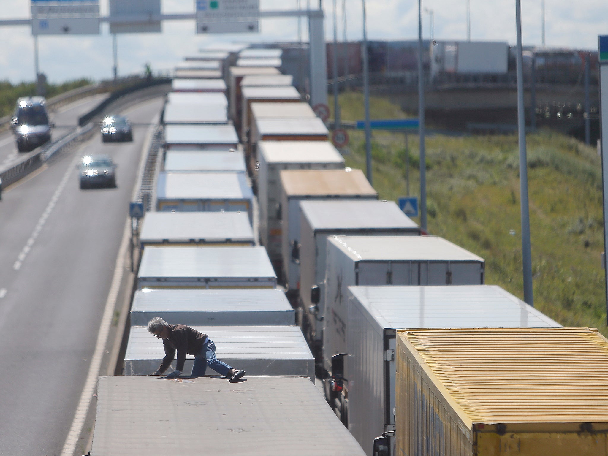 A driver climbs on his truck as he waits to cross the English channel, in Calais