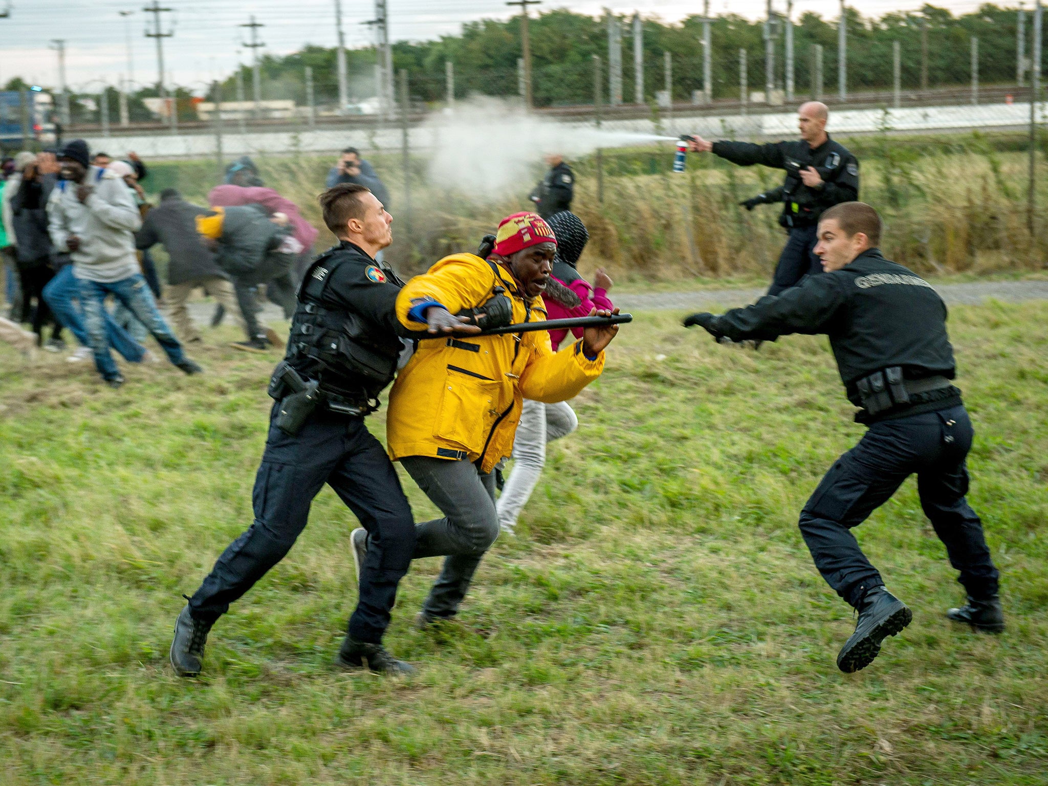 French gendarmes try to stop migrants on the Eurotunnel site in Coquelles near Calais