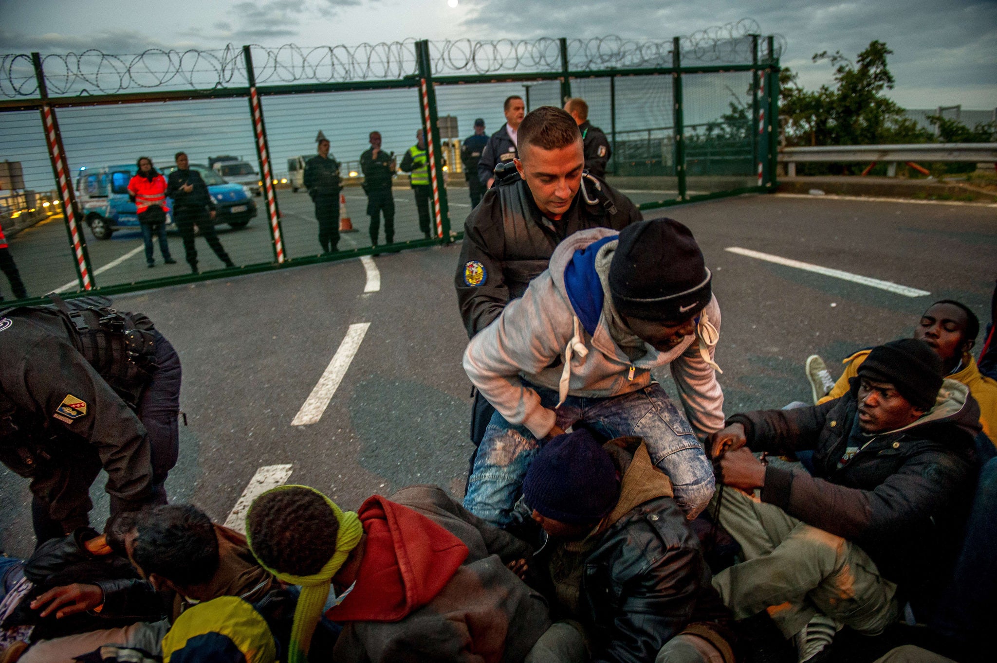 French gendarmes try to separate migrants on the Eurotunnel site near the boarding docks in Coquelles