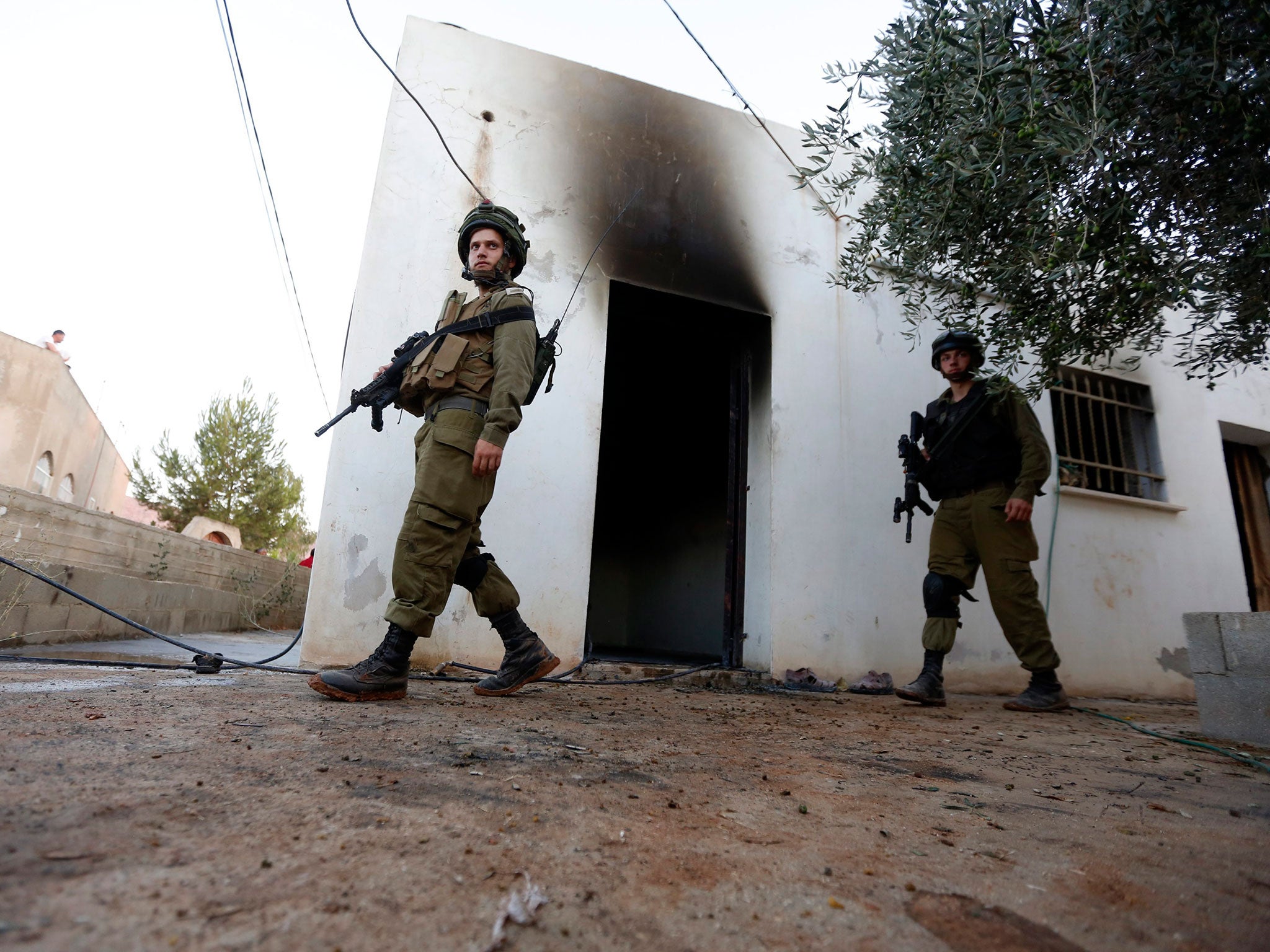 Israeli soldiers check the damage to the Palestinian fire damaged house in the West Bank village of Douma near Nablus City, 31 July 2015