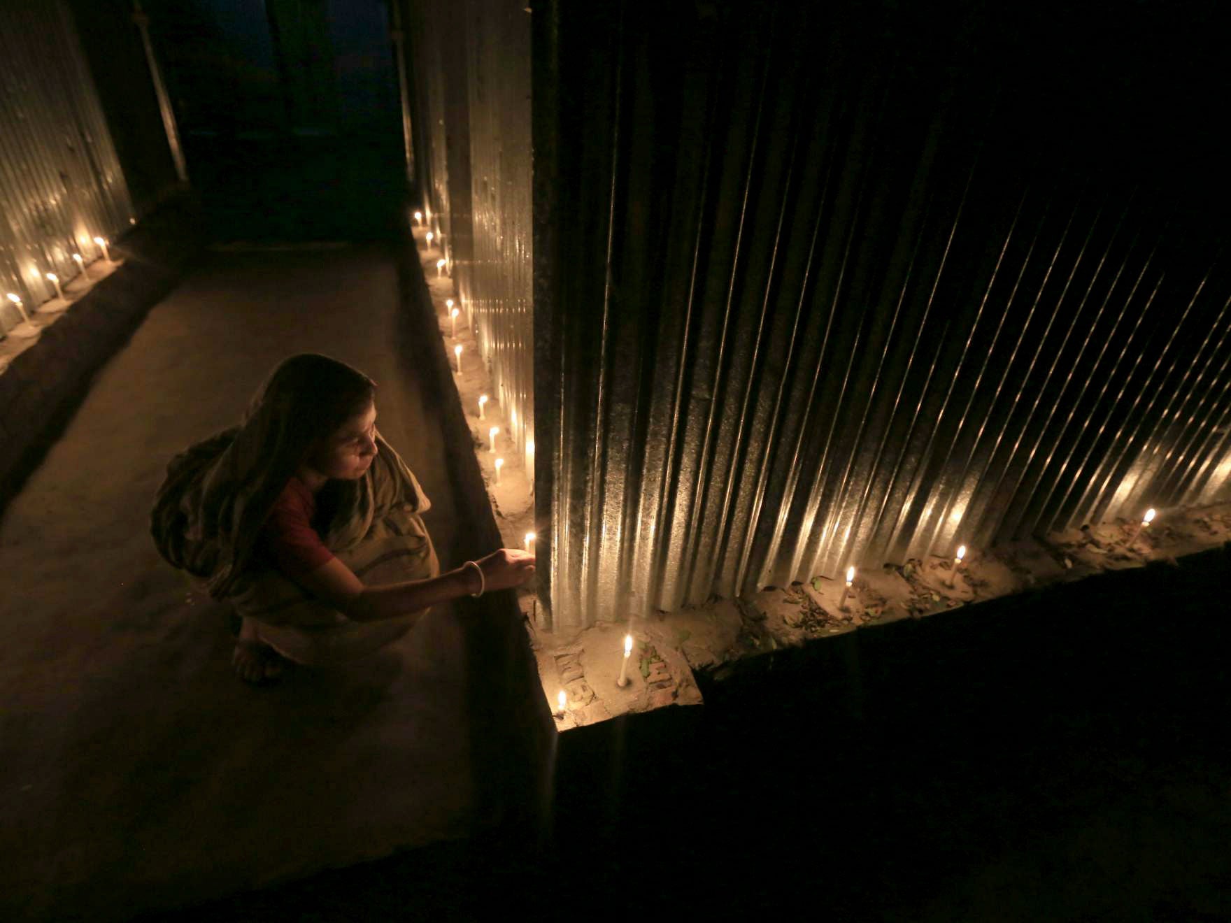 A woman lights candles in celebration at Dashiarchhara, Bangladesh.