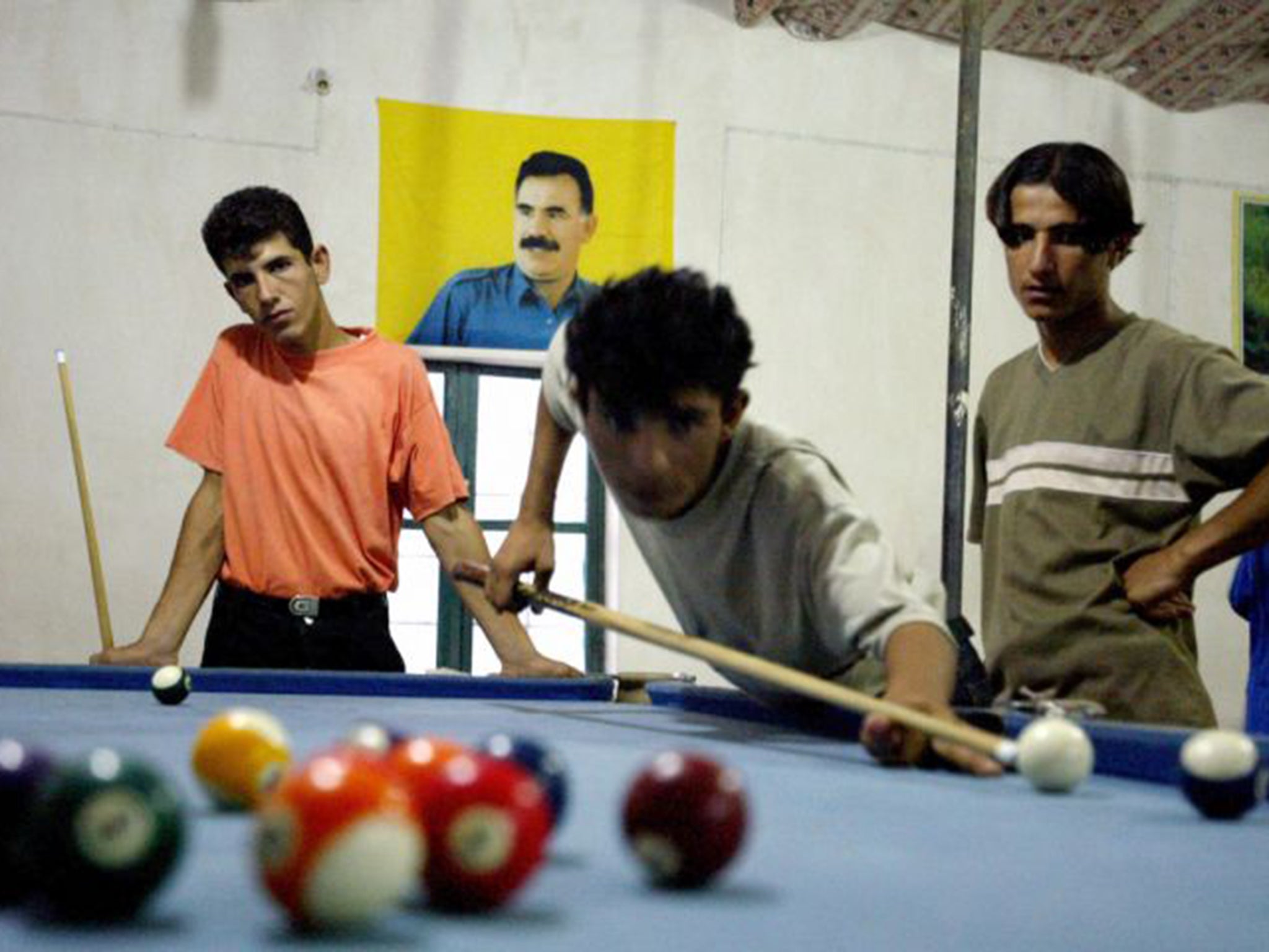 Kurdish men at the Makhmour refugee camp. Behind them is a poster of the Kurdish leader Abdullah Ocalan