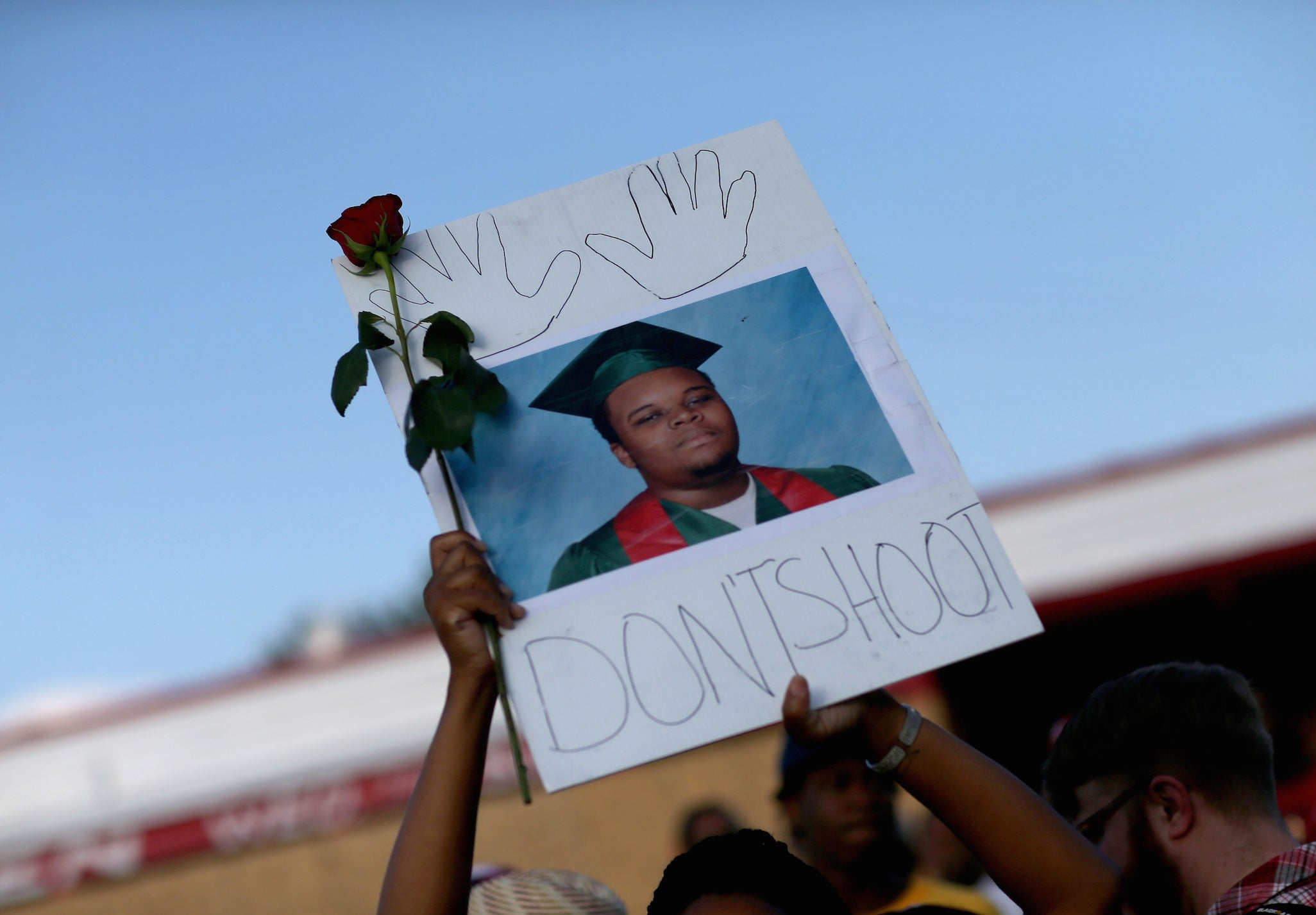 A demonstrator holds a sign reading "Dont Shoot" with images of Michael Brown on 17 August 2014 in Ferguson, Missouri. (Image: Getty)