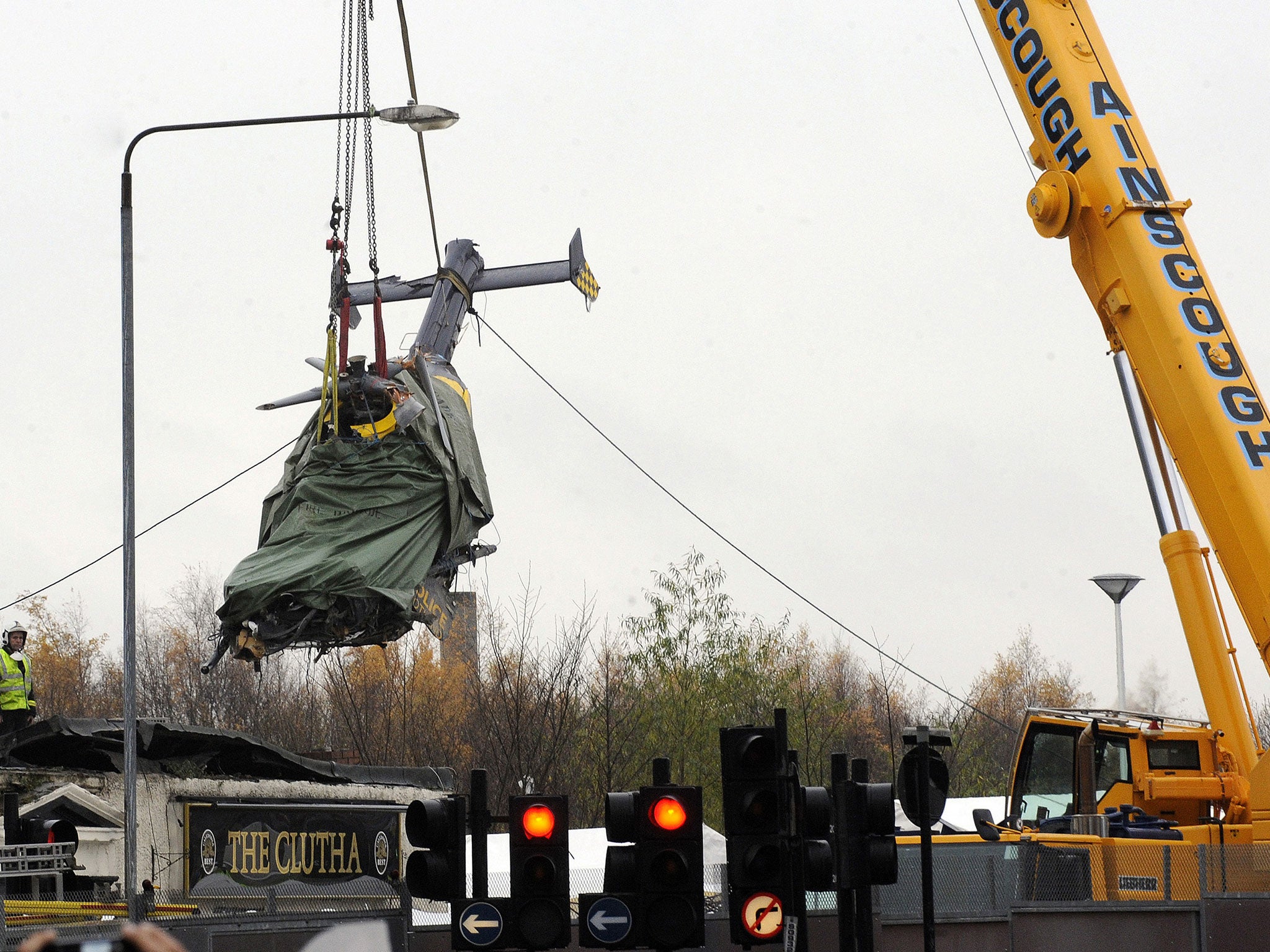 Emergency services workers look on as the wreckage of a police helicopter is winched from the collapsed roof of a pub in Glasgow 2 December 2013.